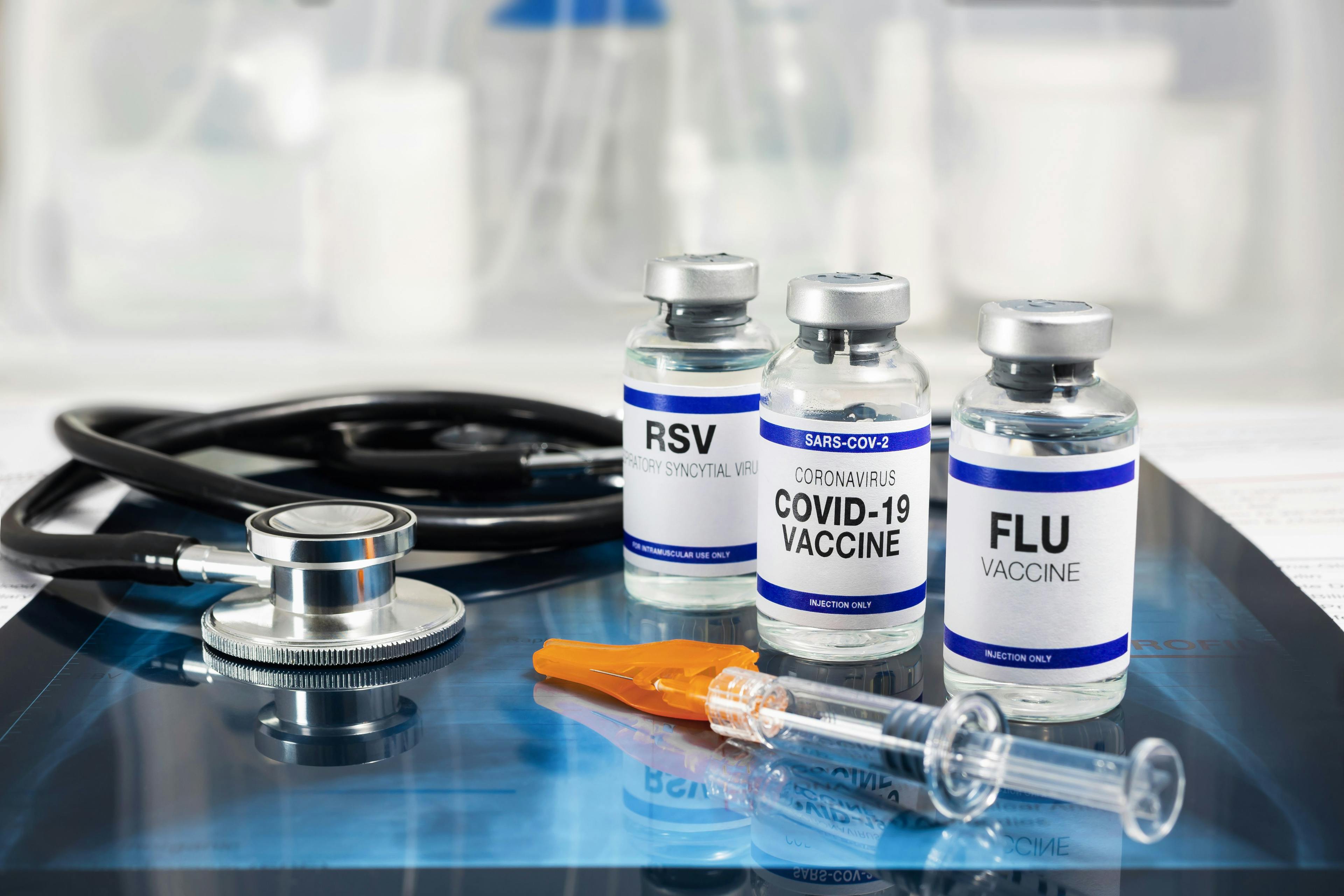 Bottles of vaccine for Influenza Virus, Respiratory Syncytial virus and Covid-19 for vaccination. Flu, RSV and Sars-cov-2 Coronavirus vaccine vials over Radiography pulmonar with stethoscope. Image credit: angellodeco - stock.adobe.com