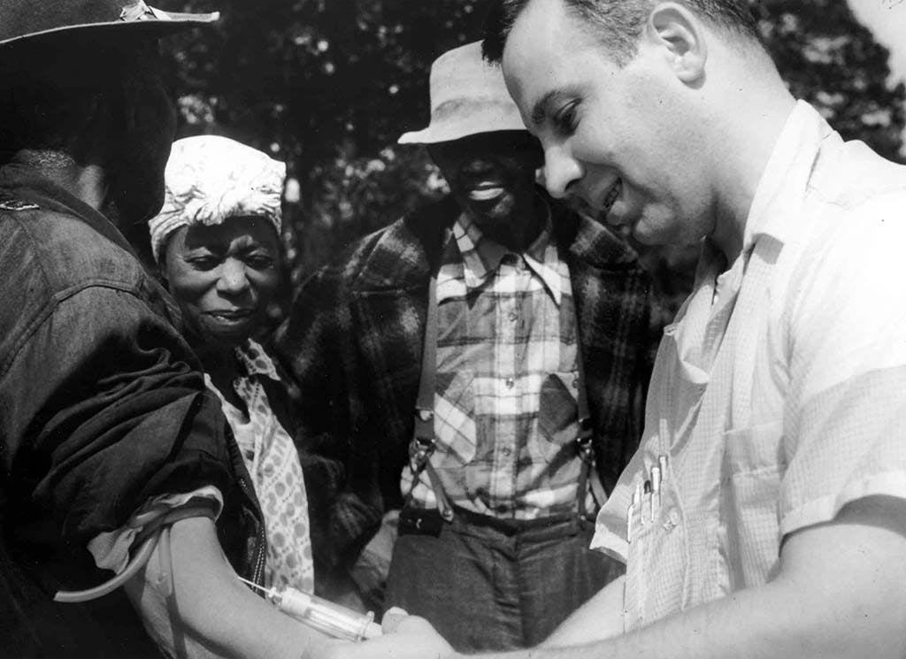 A physician draws blood from a study participant in the USPHS Syphilis Study at Tuskegee, 1932. Image Credit: US National Archives