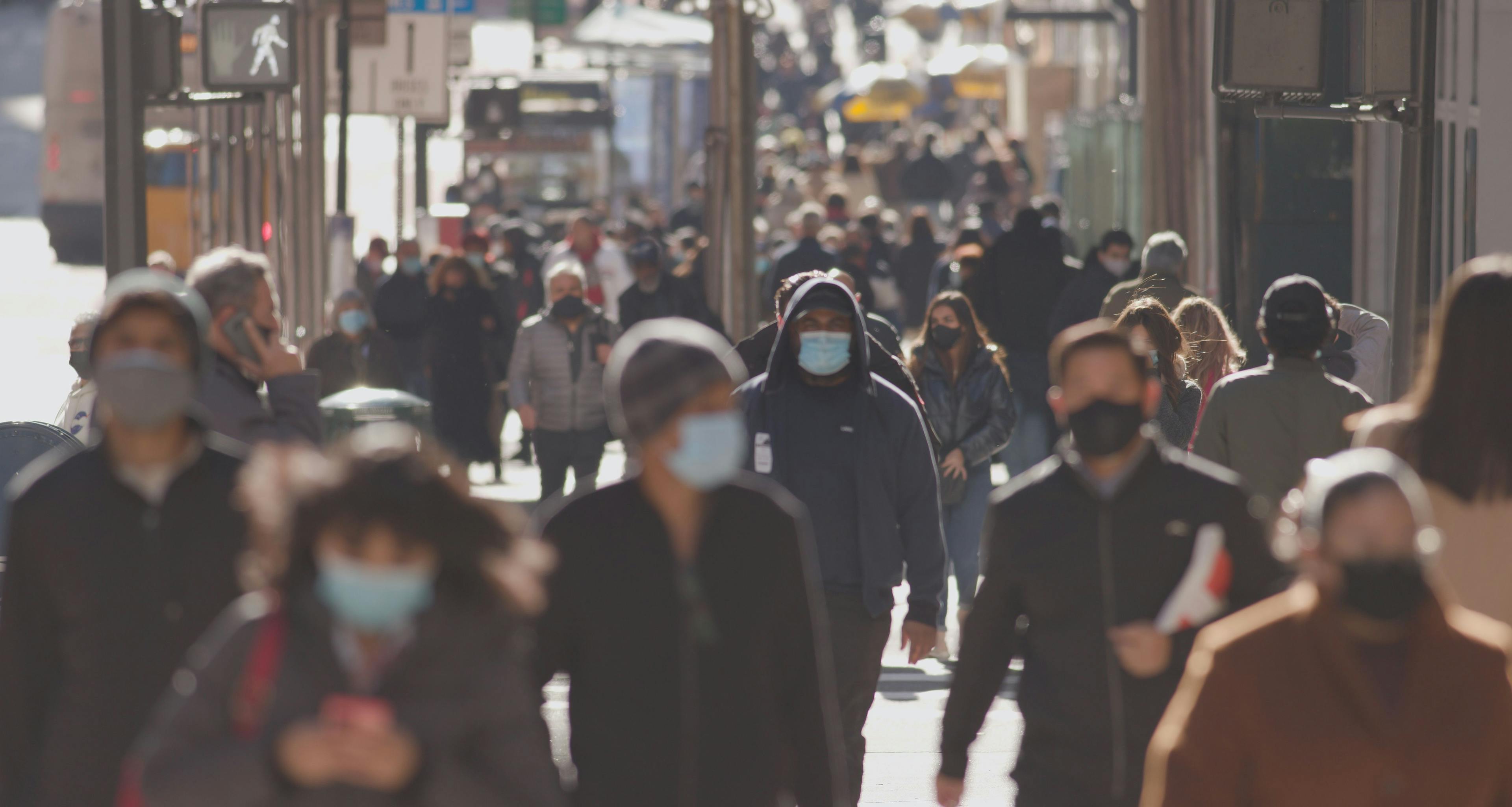 Anonymous crowd of people walking street wearing masks during covid 19 coronavirus pandemic- Image credit: Blvdone | stock.adobe.com