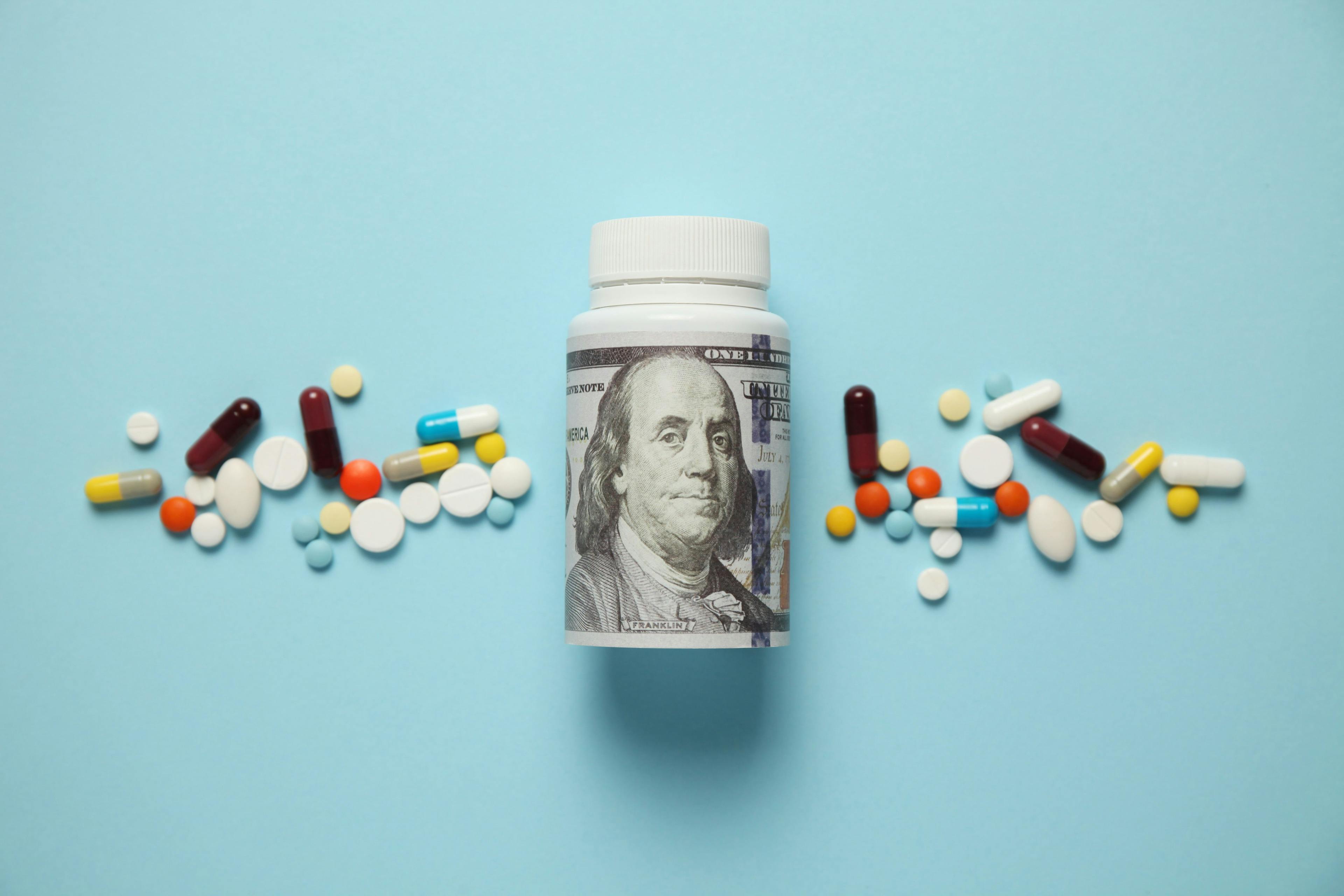 Money and pills of different colors on blue background. Rising cost of health care - Image credit: Andrii Zastrozhnov | stock.adobe.com