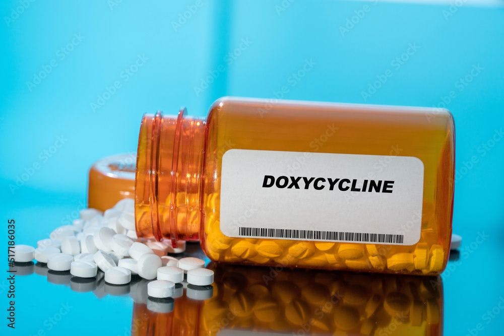 Doxycycline white medical pills and tablets spilling out of a drug bottle. | Image Credit: luchschenF - stock.adobe.com