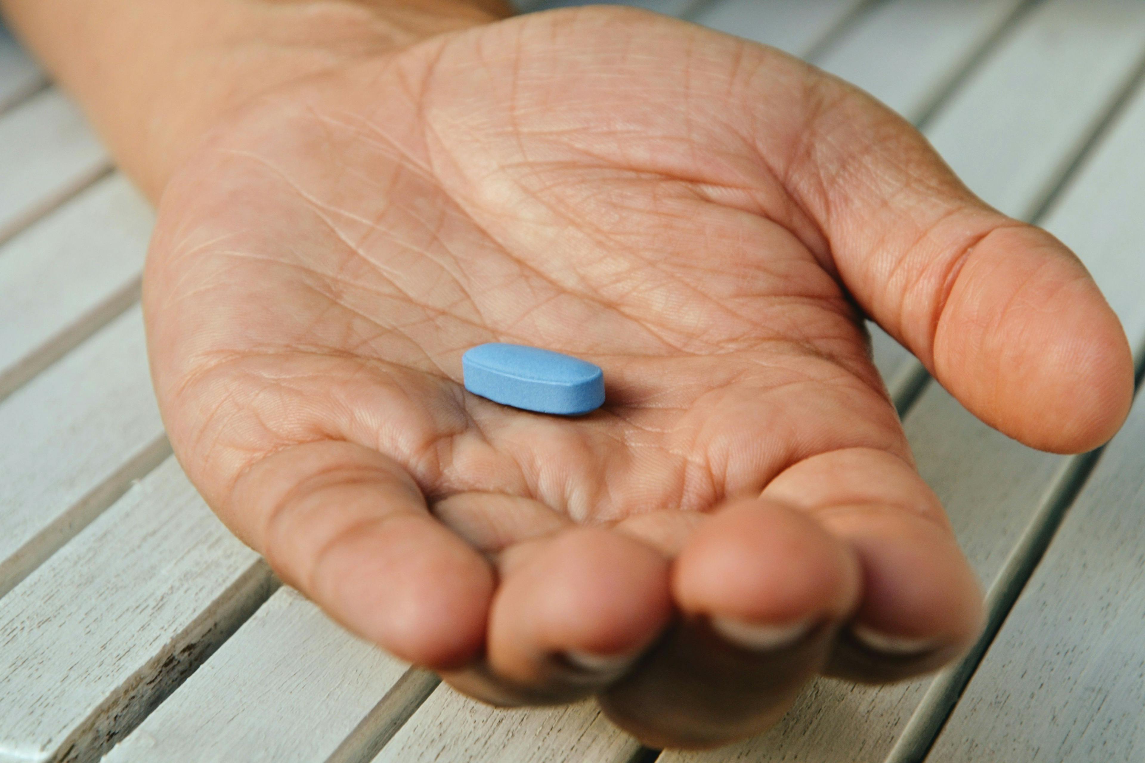 Man holding viagra pill -- Image credit: PaulSat | stock.adobe.com
