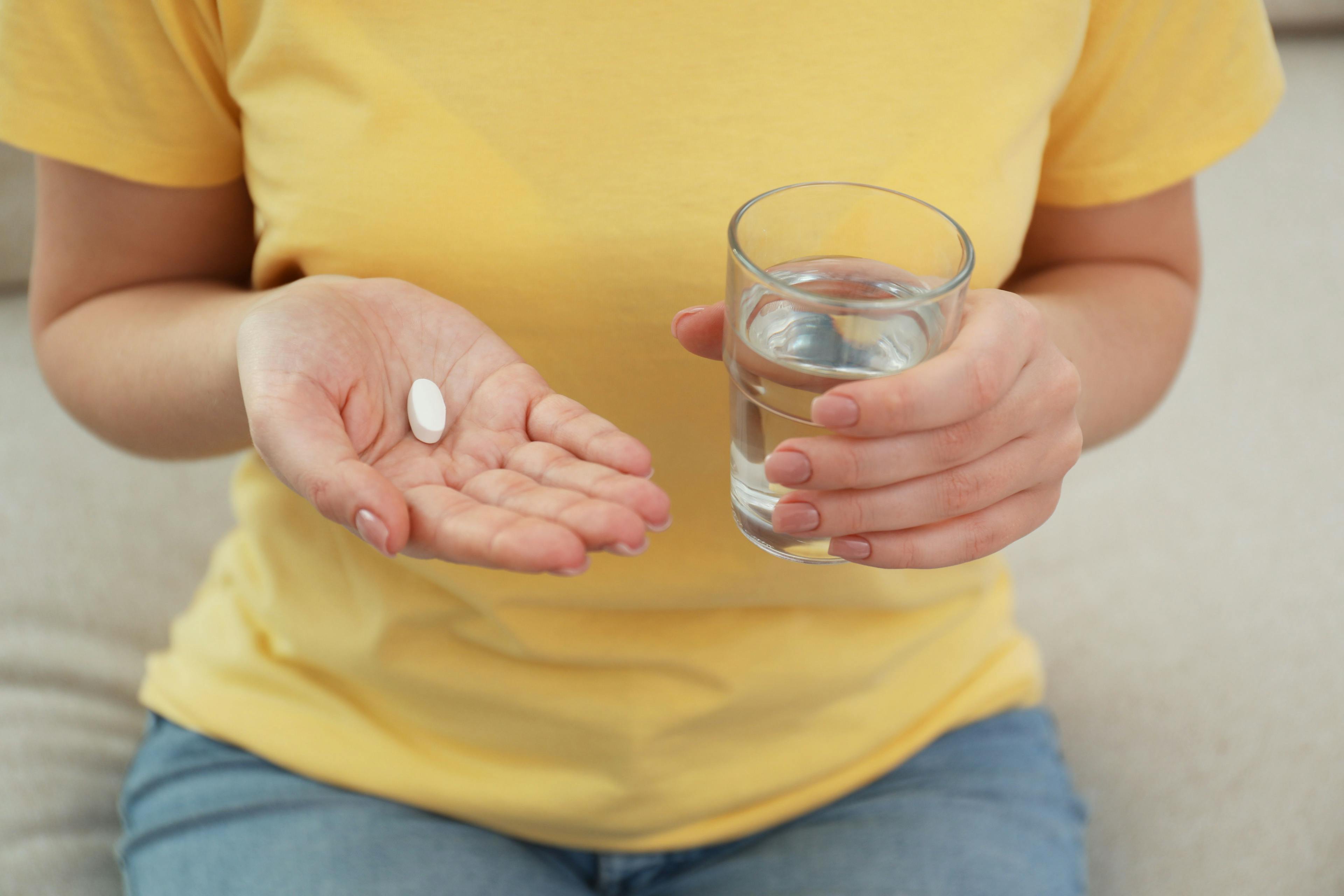 Woman holding a pill and glass of water