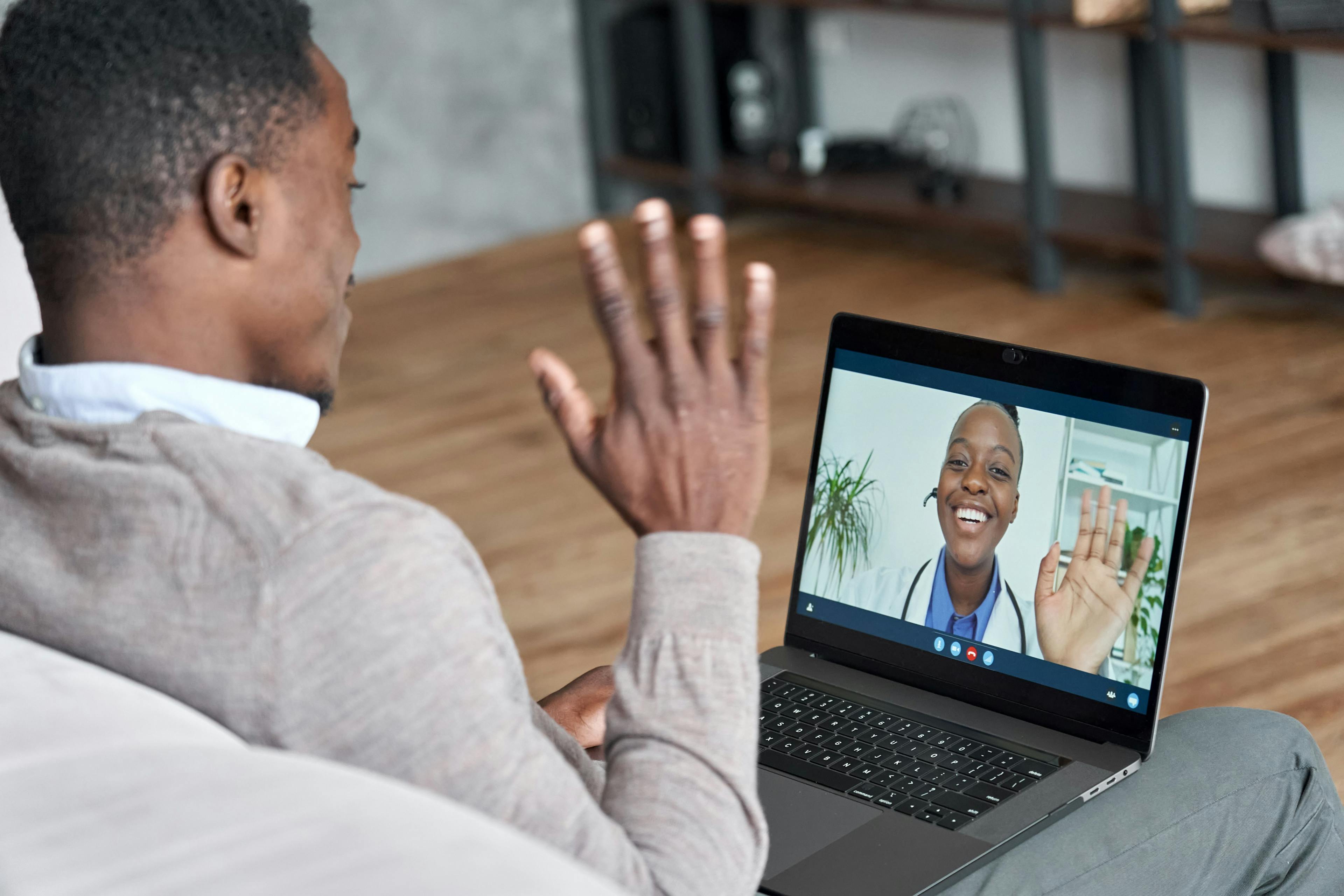 Male black patient talking on conference video call to female african doctor. Virtual therapist consulting young man during online appointment on laptop at home. Telemedicine chat, telehealth meeting | Image Credit: insta_photos - stock.adobe.com