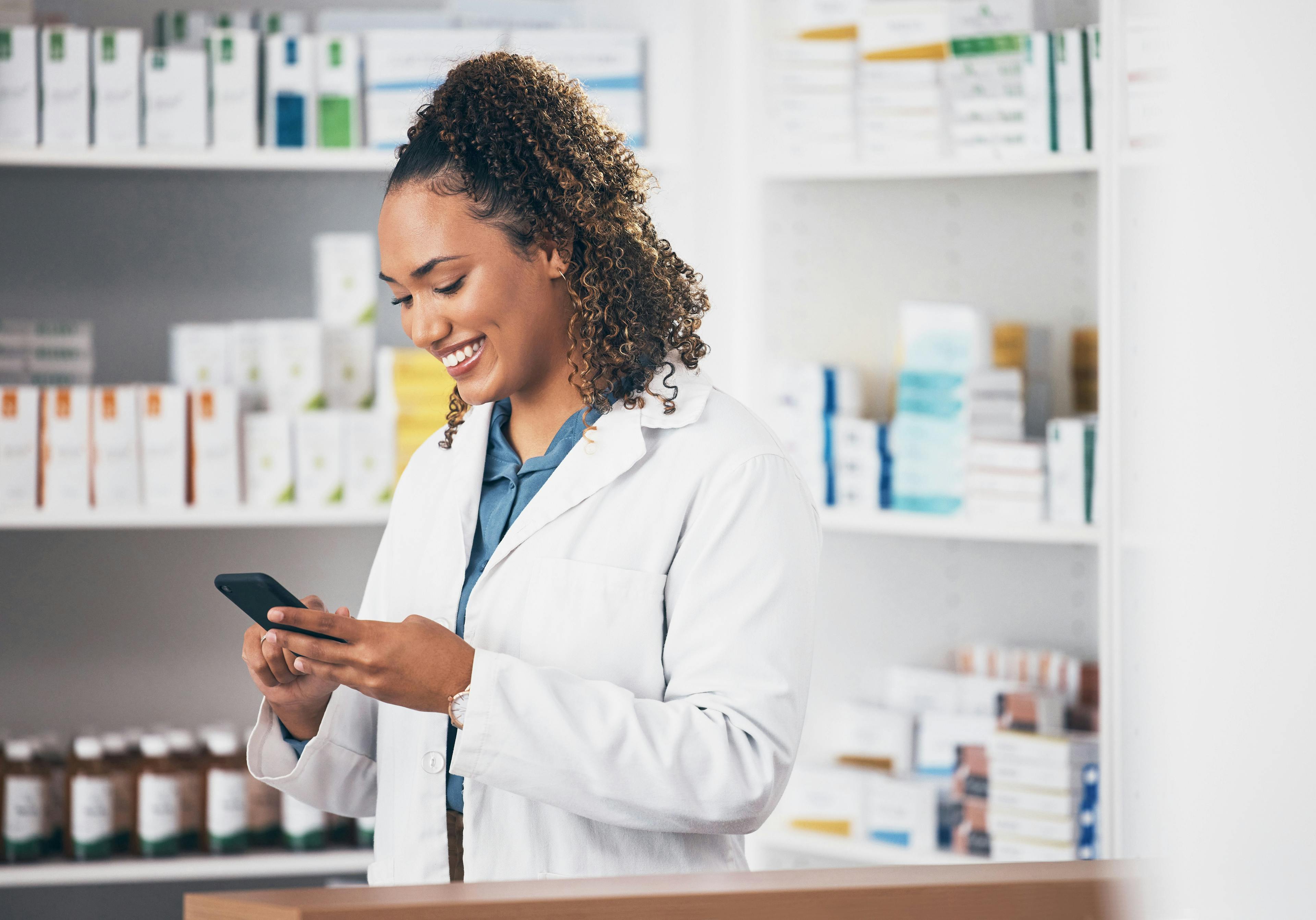 Pharmacist texting in pharmacy to contact, email communication or reading chat with patient. | Image Credit: Rene La/peopleimages.com - stock.adobe.com
