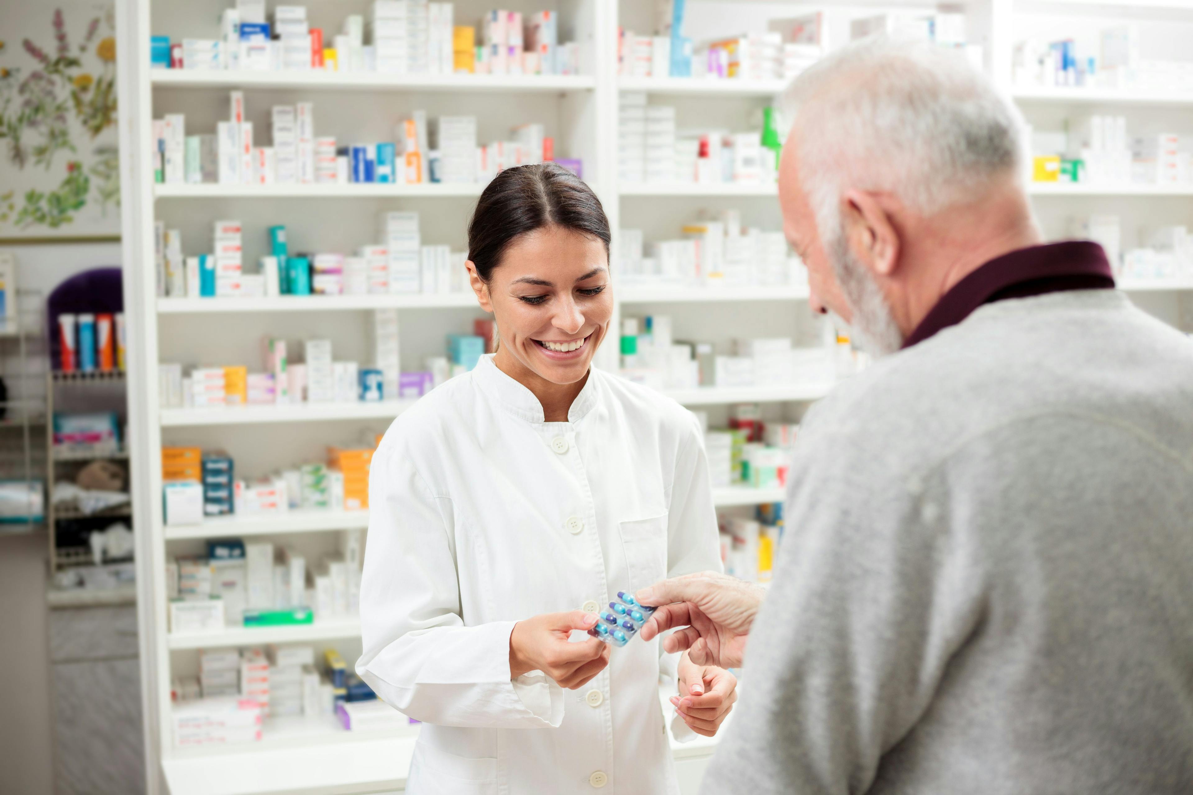 happy pharmacist giving medications to senior man customer | Image Credit: Ivan - stock.adobe.com