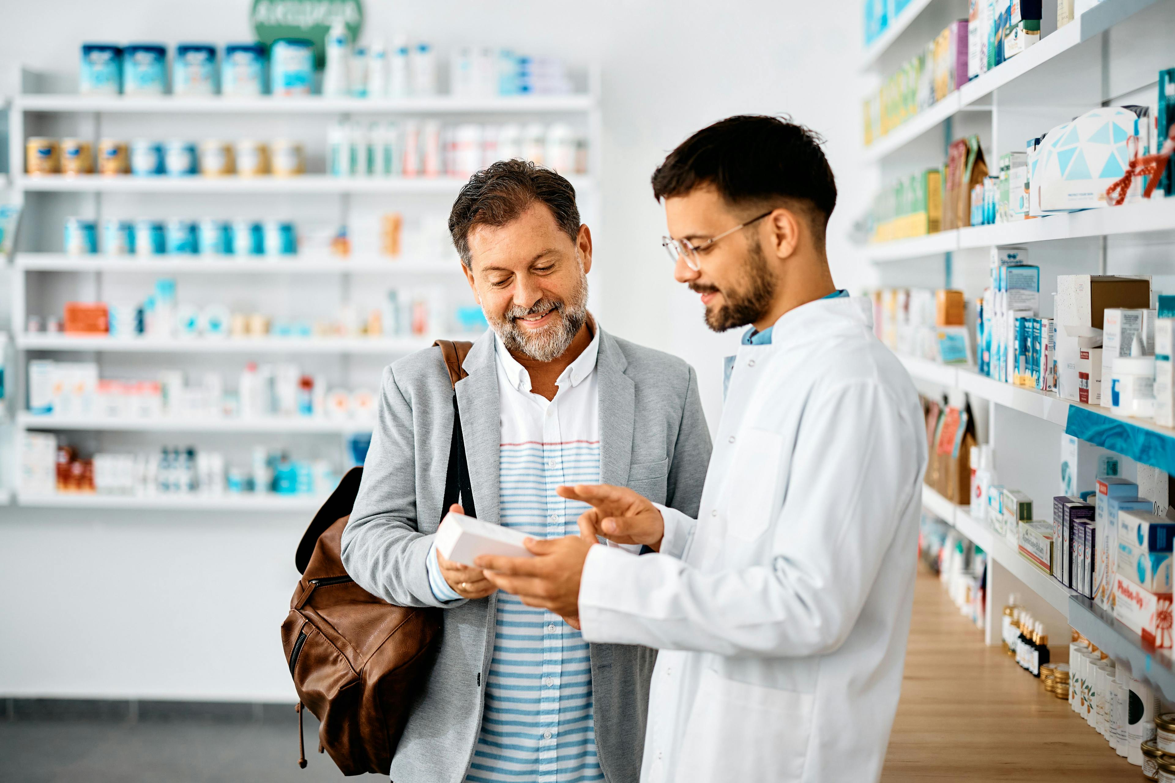 Happy man chooses medicine with help of young pharmacist in drugstore | Image Credit: Drazen - stock.adobe.com