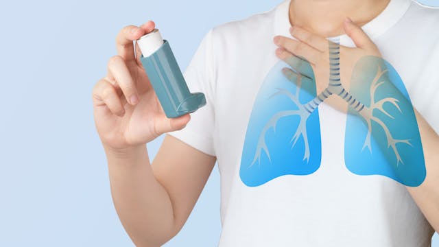 Young woman using blue asthma inhaler