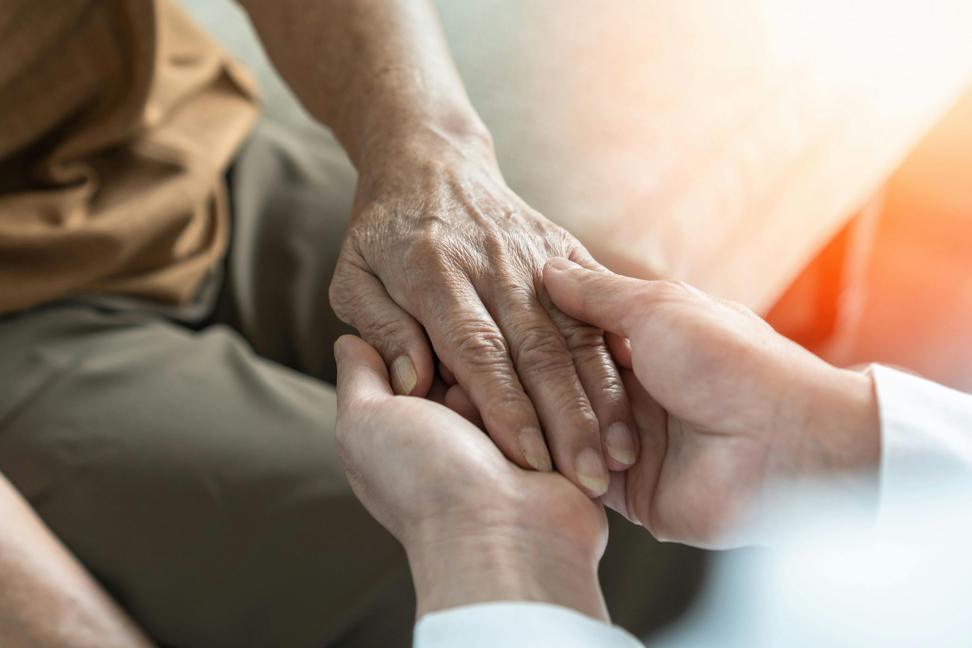 Health care worker holding the hand of an elderly patient