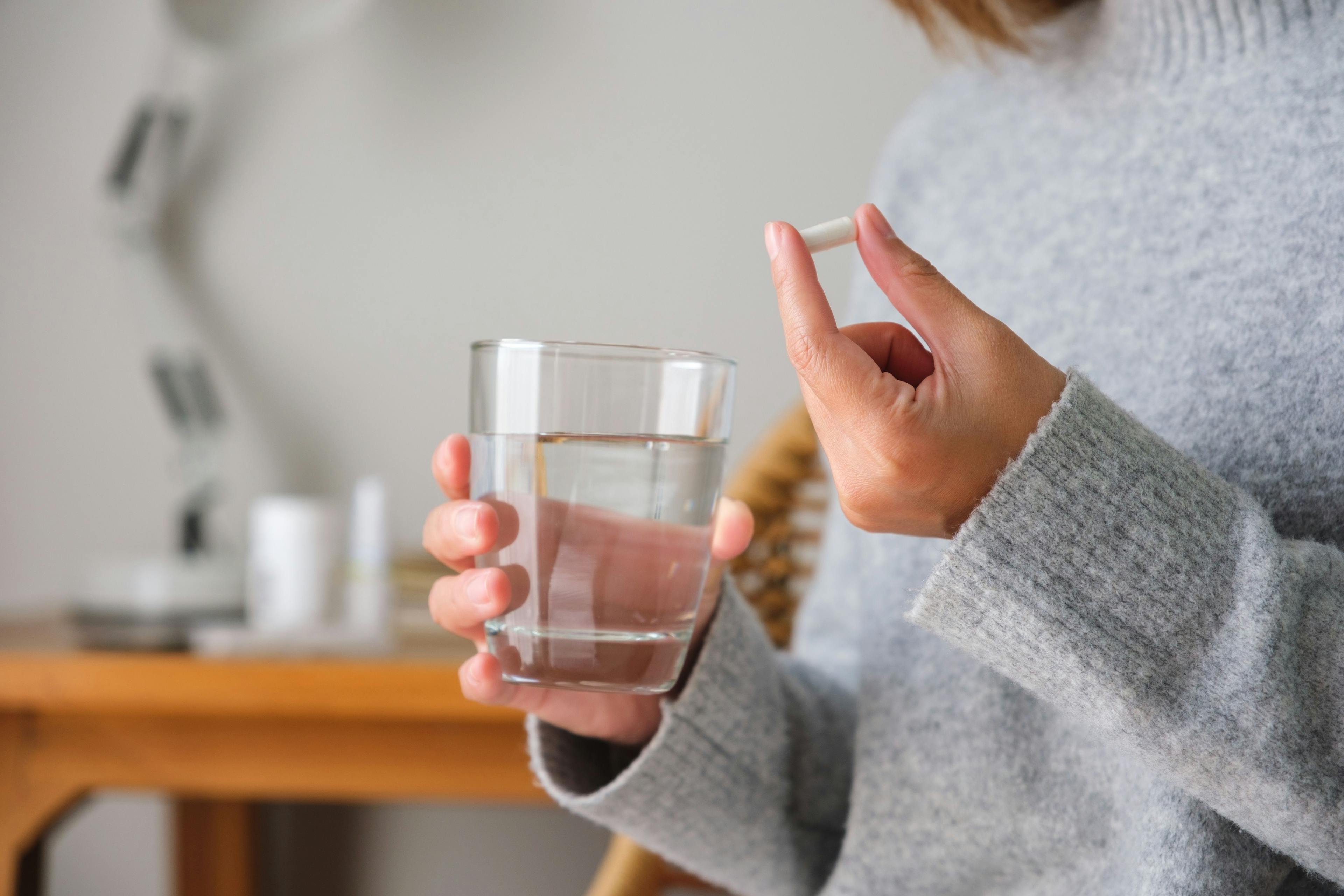 Woman holding an oral antibiotic and a glass of water