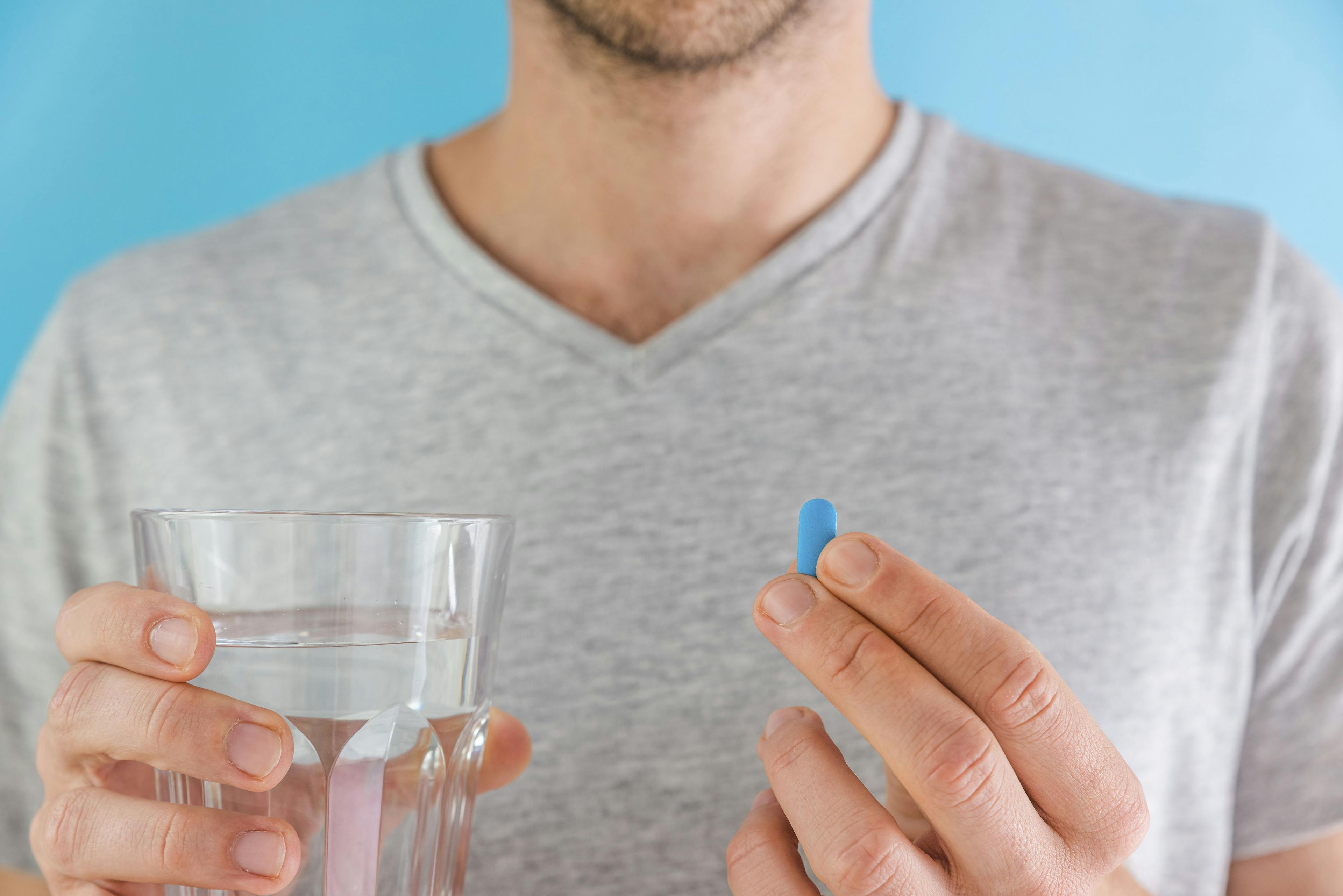 Man holding oral PrEP pill and a glass of water