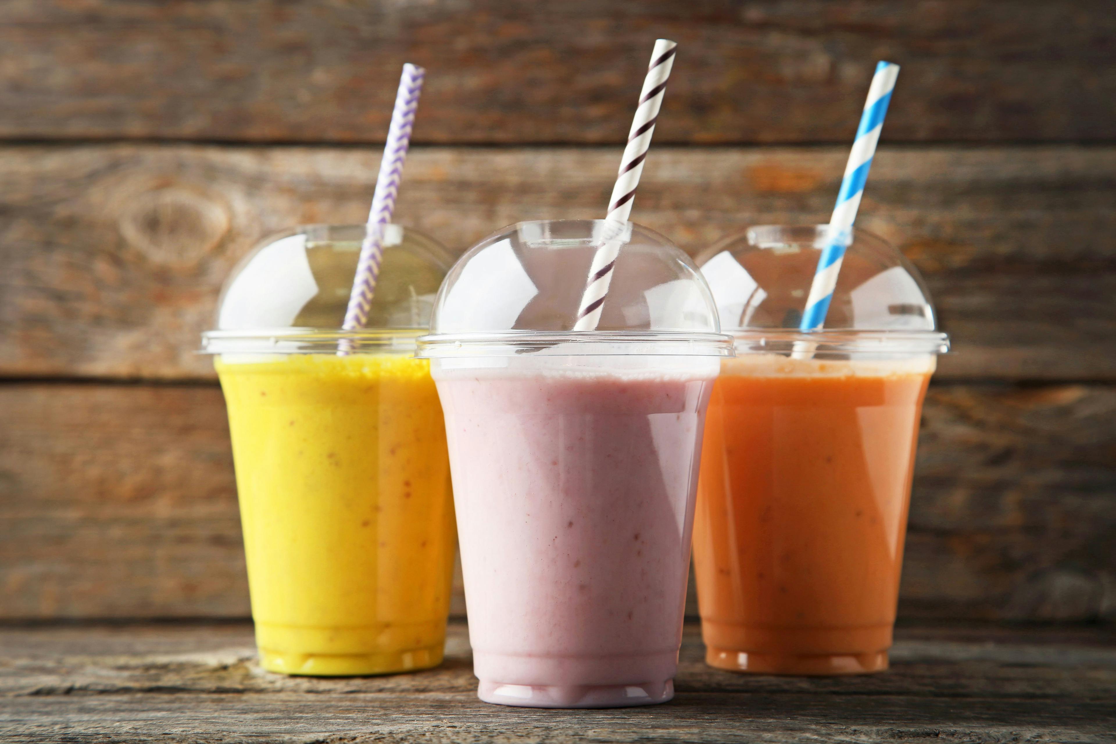 Sweet smoothie in plastic cups on wooden table | Image Credit: 5second - stock.adobe.com