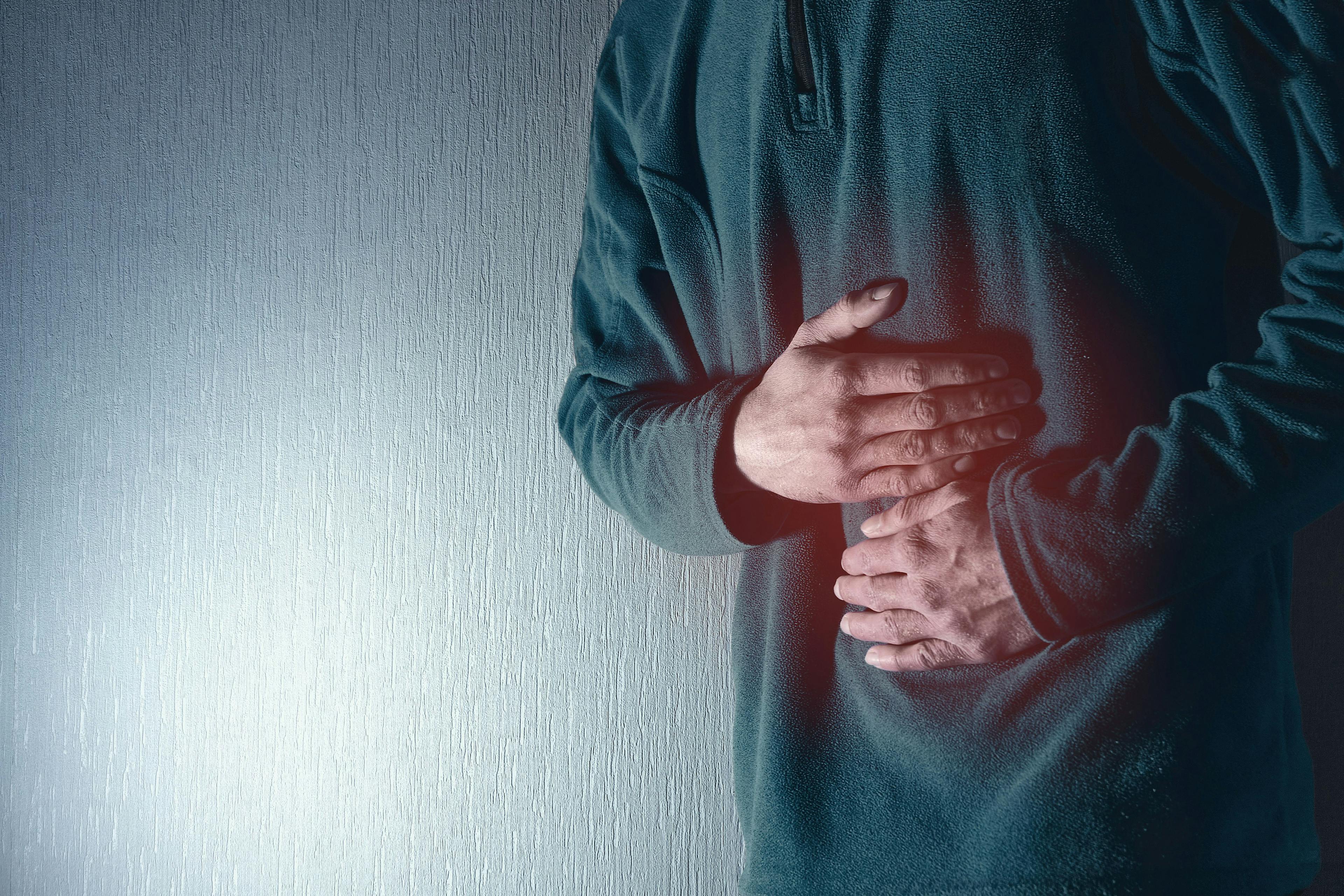 Man holds his belly with both hands. Stomach ache. Gastritis. Blue grey background. - Image credit: Fotografie-Schmidt | stock.adobe.com