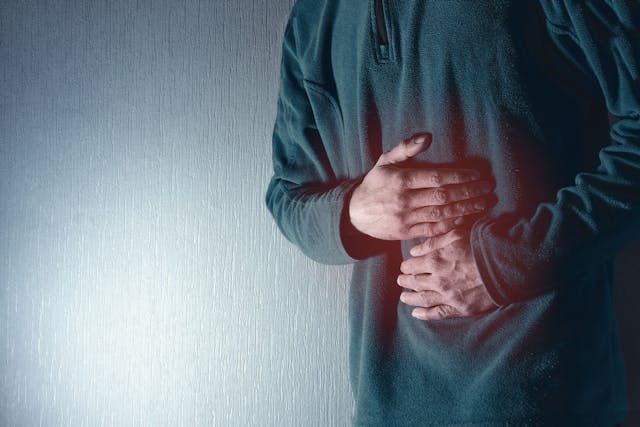 Man holds his belly with both hands. Stomach ache. Gastritis. Blue grey background. - Image credit: Fotografie-Schmidt | stock.adobe.com