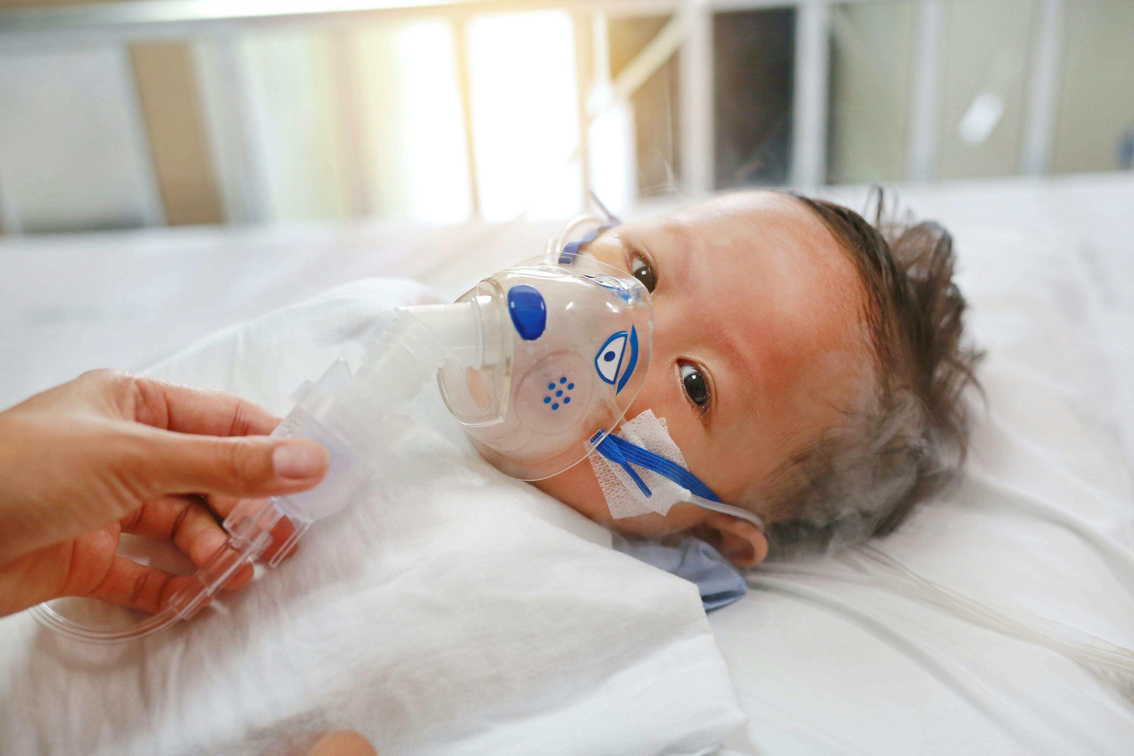 Sick baby boy applying inhale medication by inhalation mask to cure Respiratory Syncytial Virus (RSV) on patient bed at hospital -Image credit: Zilvergolf | stock.adobe.com