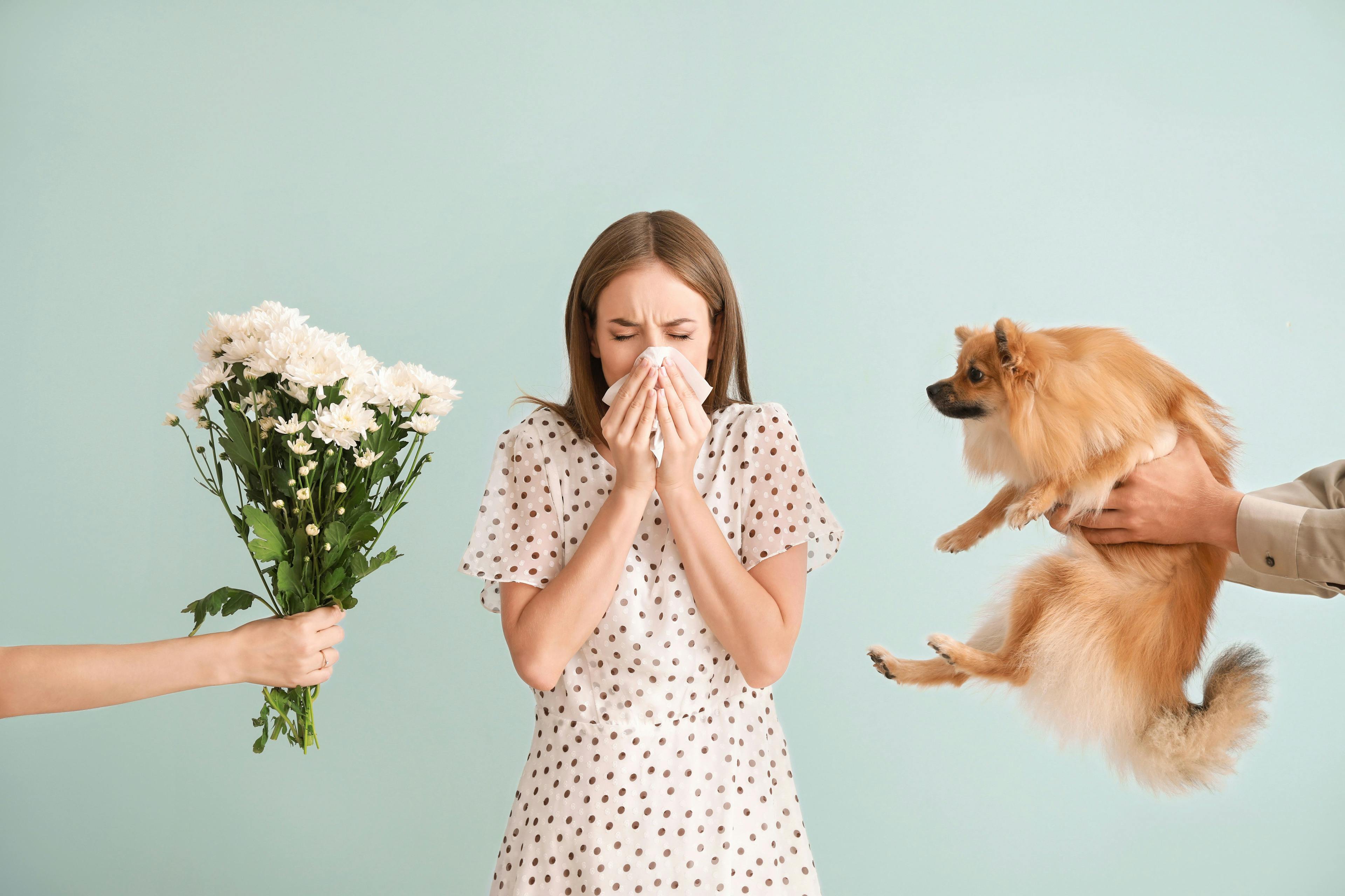 People giving flowers and dog to young woman suffering from allergy on light background | Image Credit: Pixel-Shot - stock.adobe.com