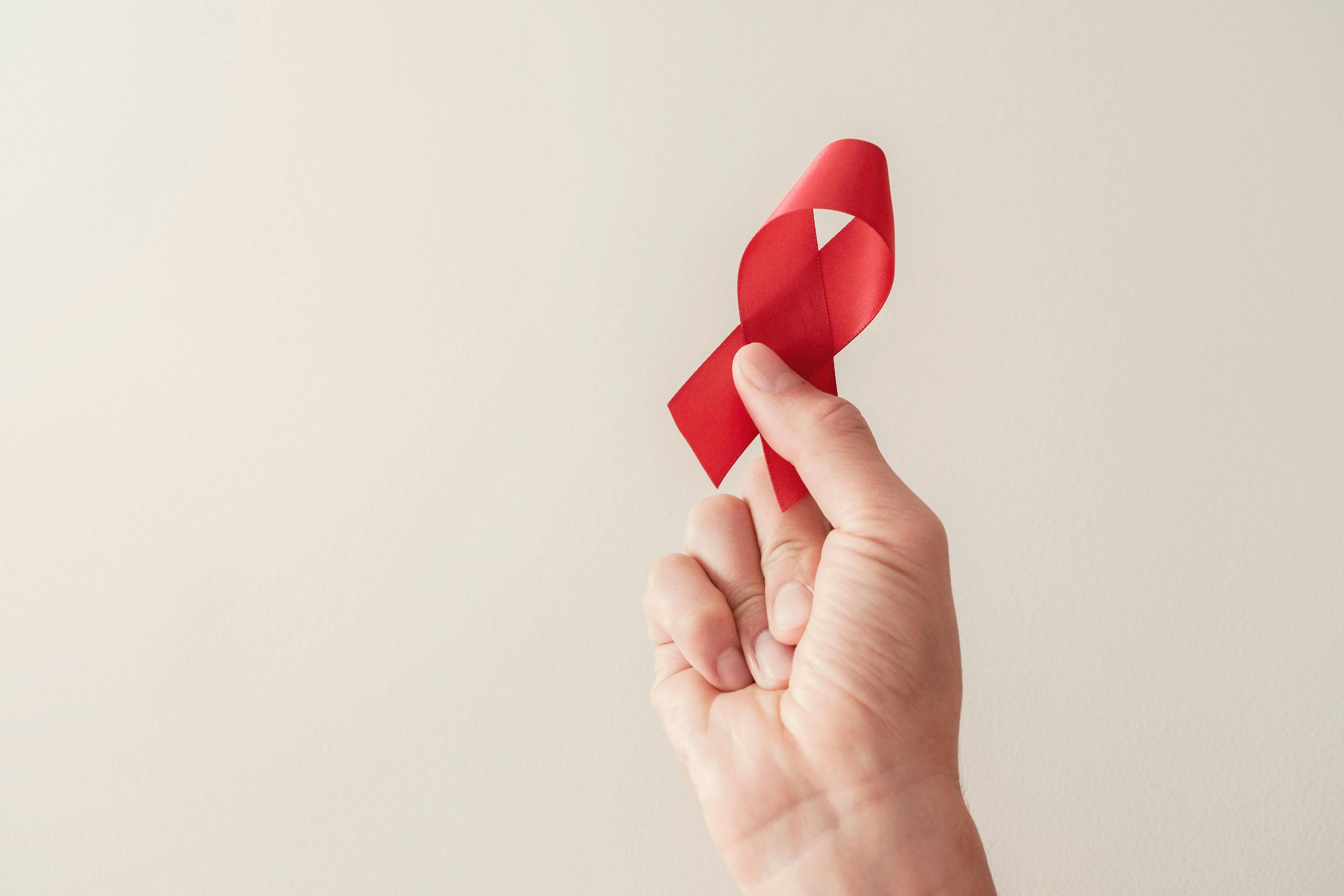 Man holding red ribbon for HIV awareness