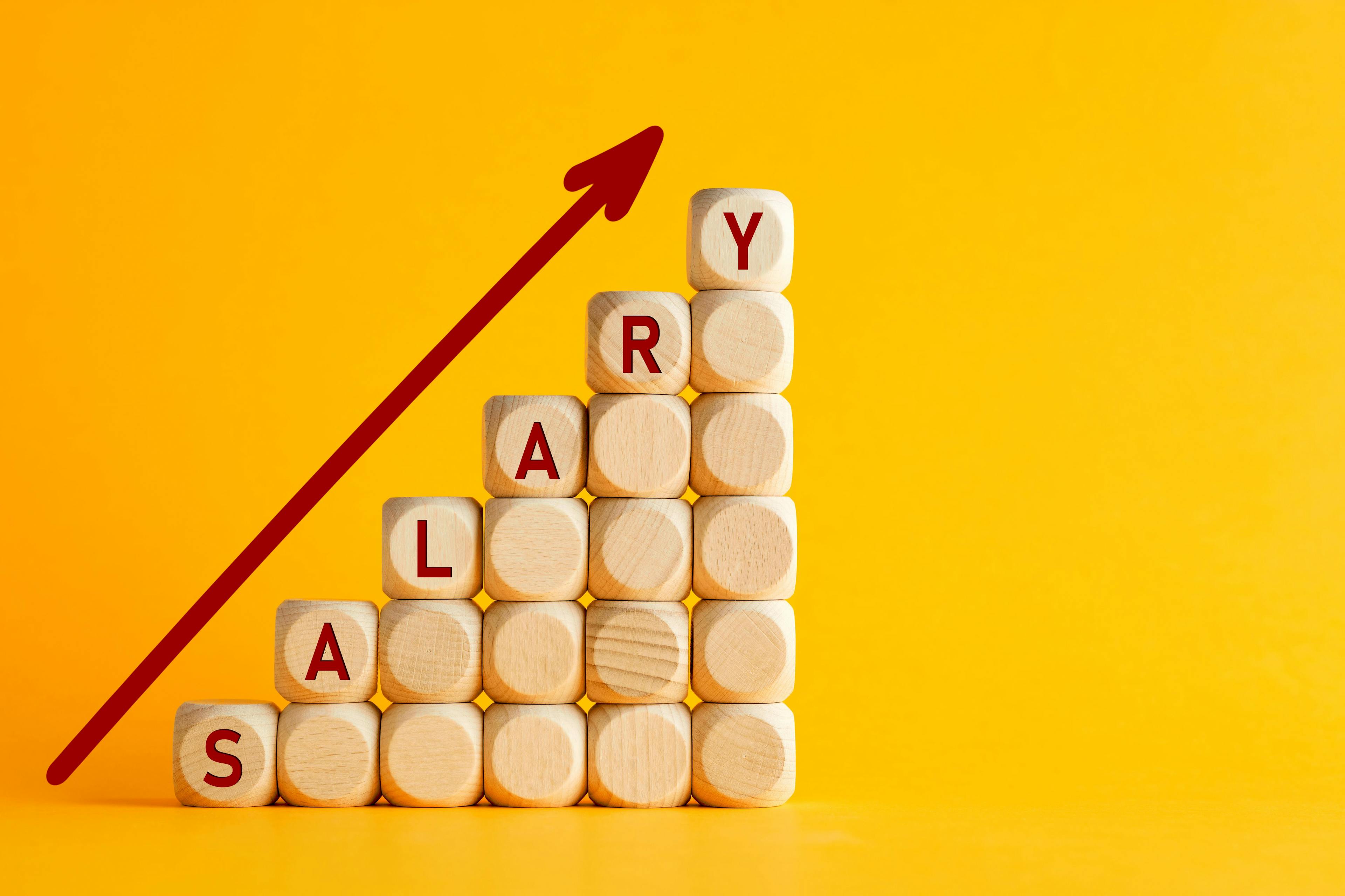 Salary raise or wage increase concept. The word salary on stacked wooden blocks with an ascending arrow icon.