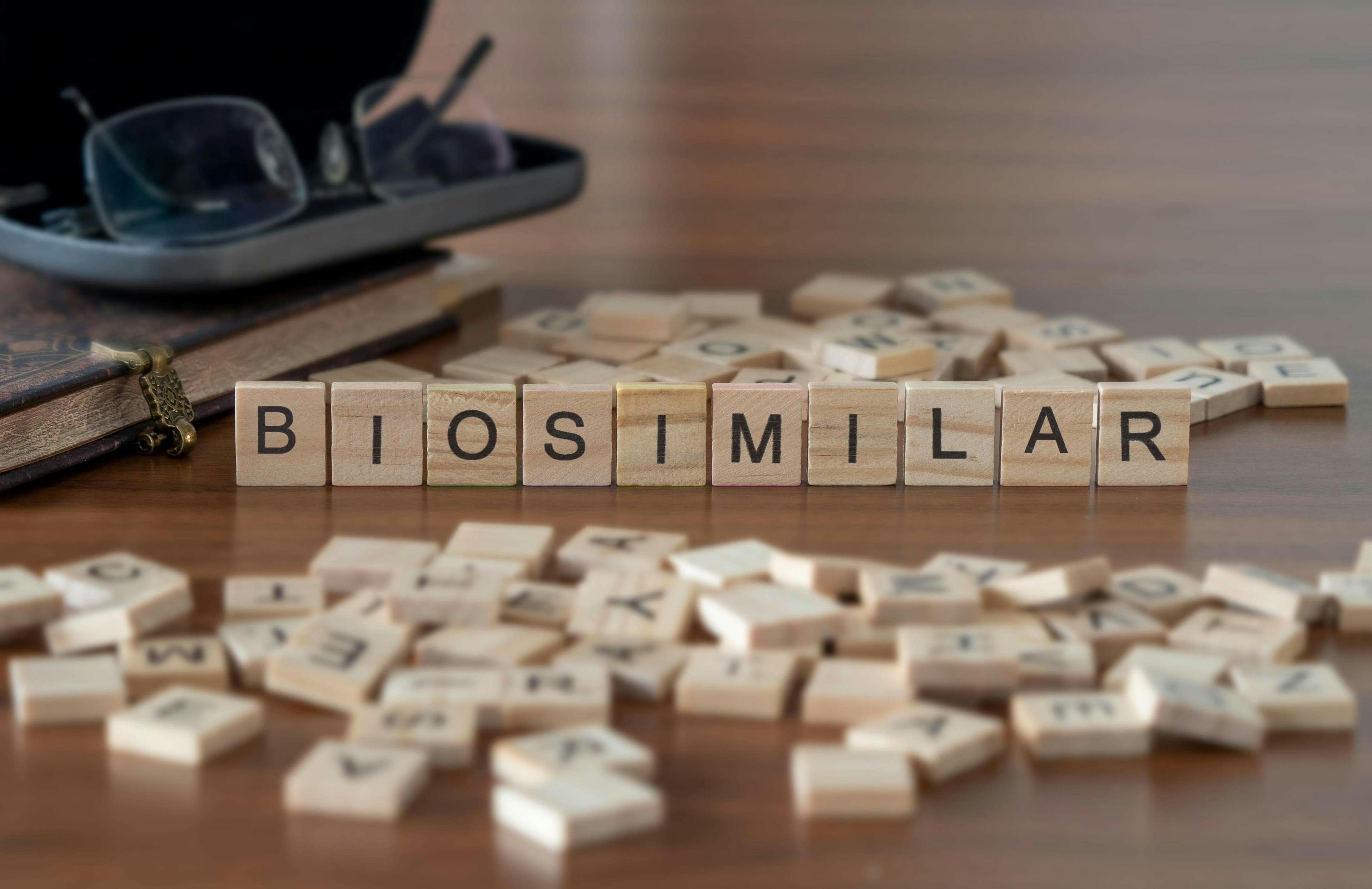 Biosimilar word or concept represented by wooden letter tiles on a wooden table with glasses and a book. Credit: lexiconimages - stock.adobe.com
