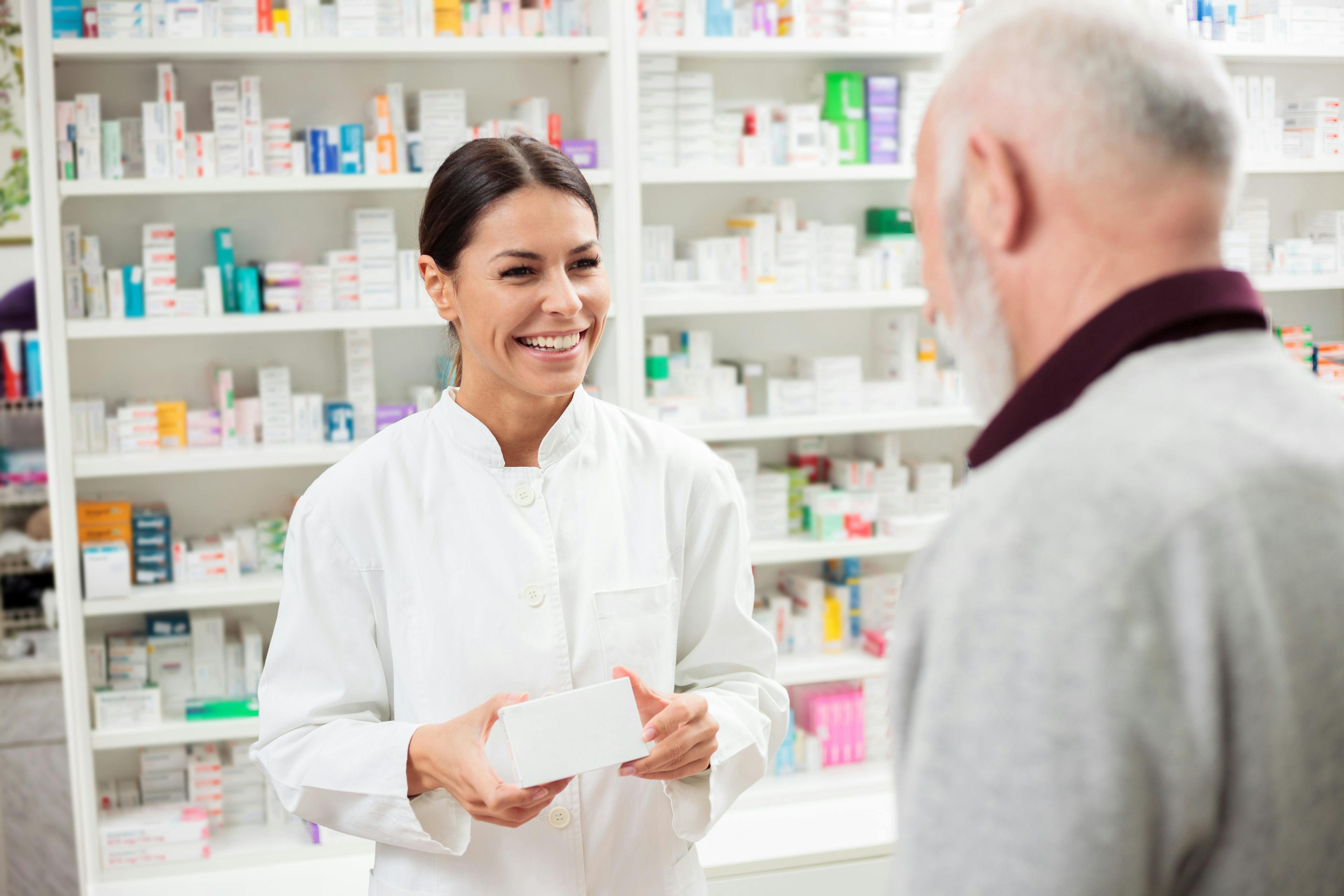 Medicine, pharmaceutics, health care and people concept - Happy female pharmacist giving medications to senior male customer - Image credit: Ivan | stock.adobe.com