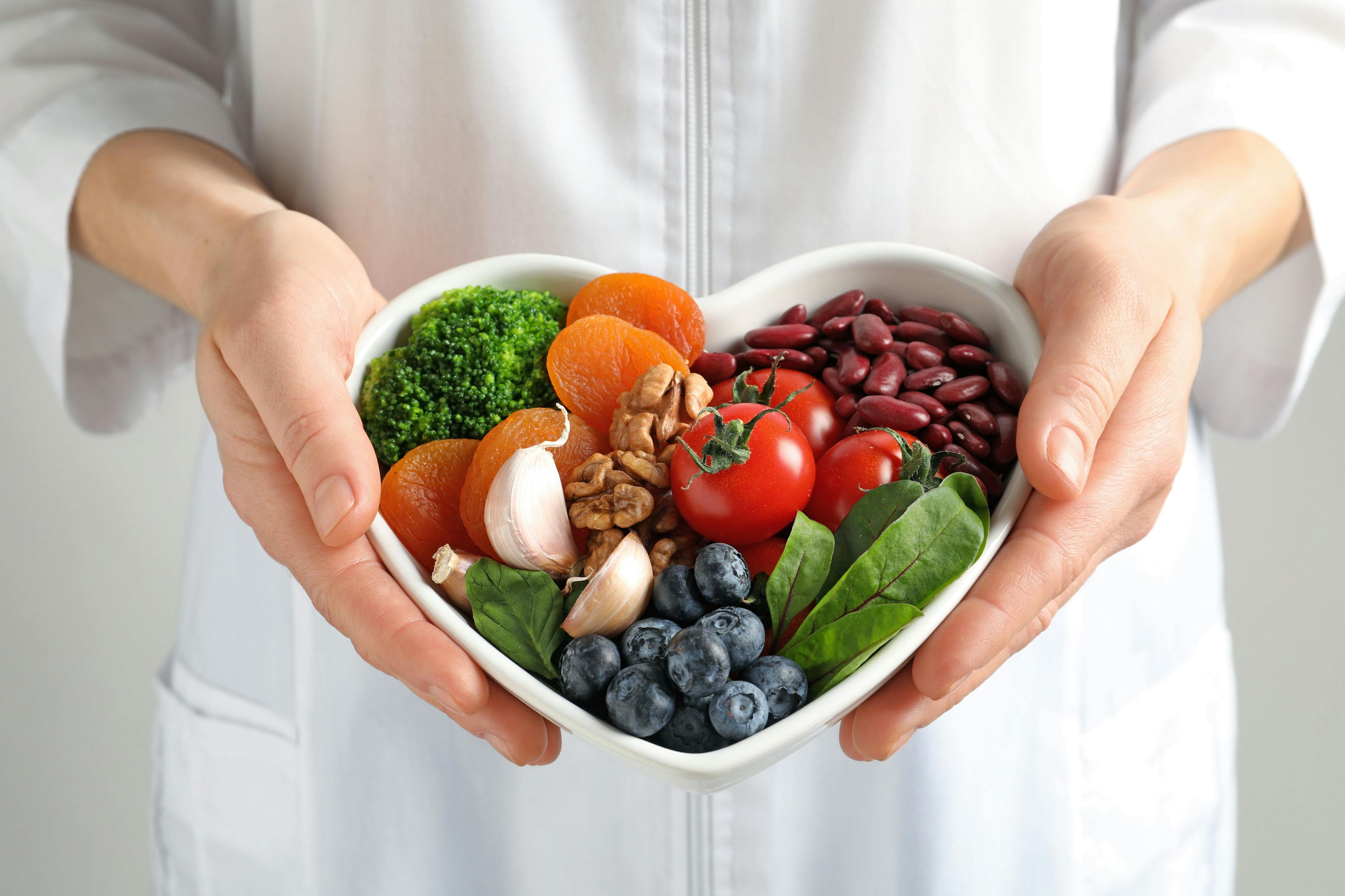 Doctor holding bowl with products for heart-healthy diet- Image credit: New Africa | stock.adobe.com