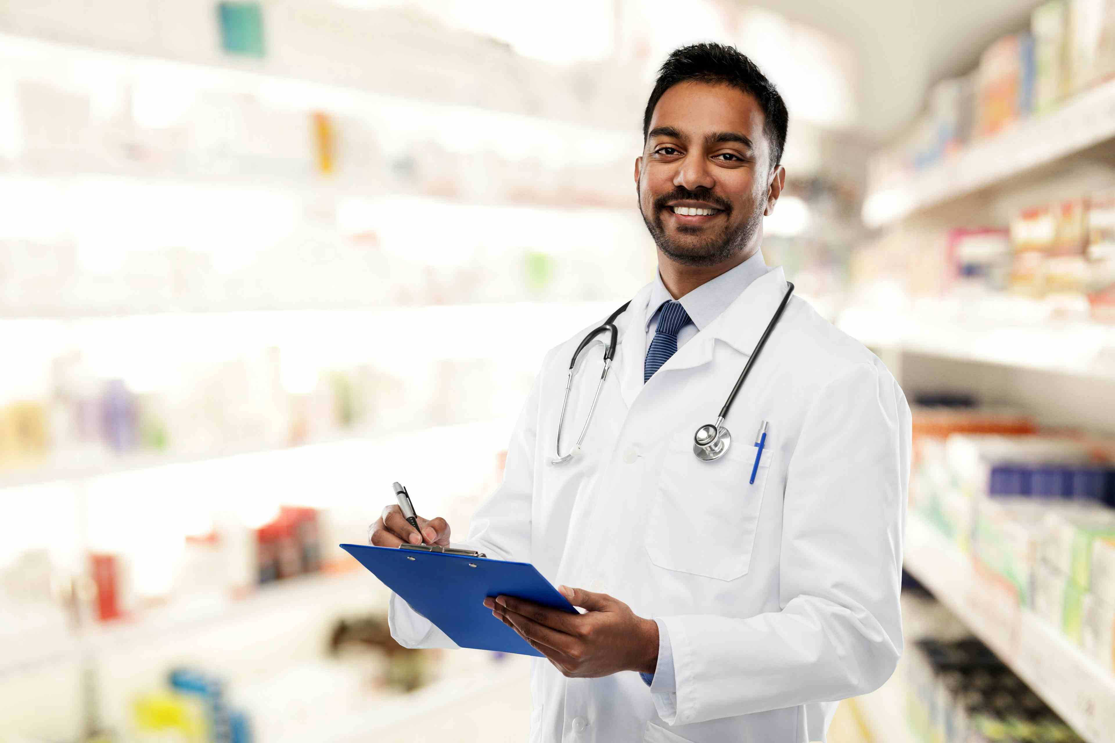 Male pharmacist in white coat with stethoscope and clipboard over drugstore background | Image Credit: Syda Productions - stock.adobe.com