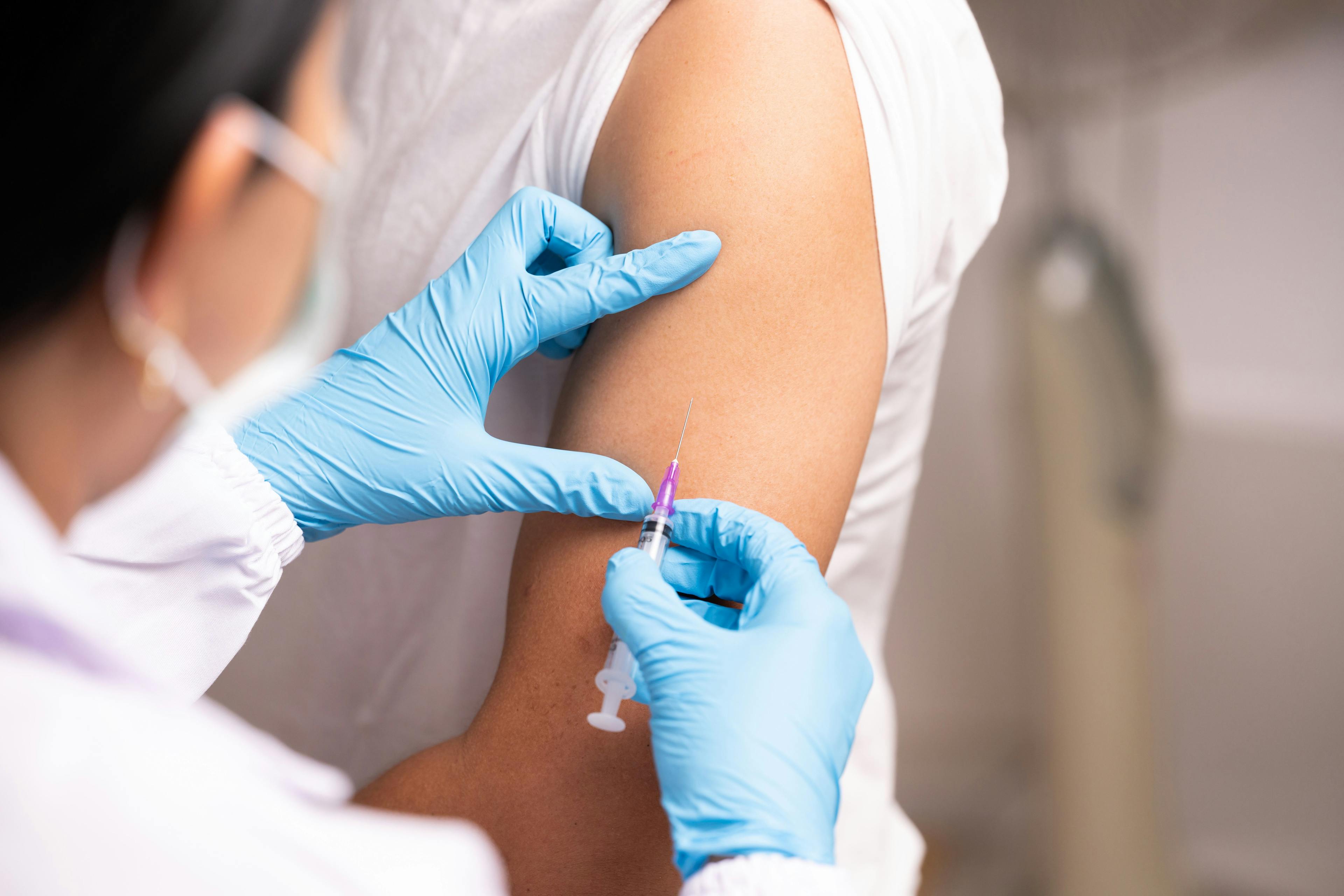 Doctor hand in blue gloves holding influenza vaccine for prevention human.Nurse holding syringe make injection in shoulder of patient in hospital.Covid-19 or coronavirus vaccine - Image credit: Arcyto | stock.adobe.com