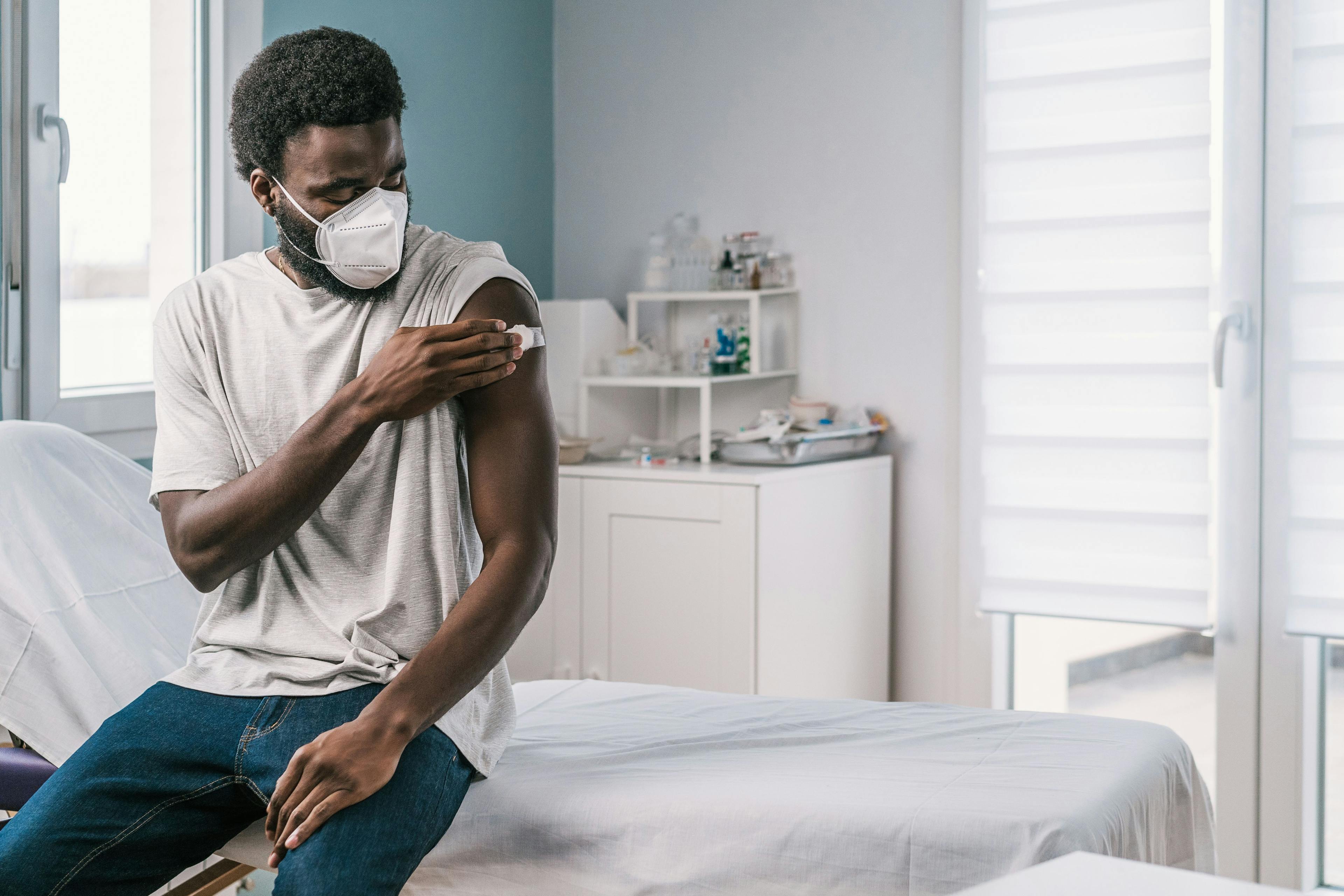 African American man patient holding cotton with alcohol disinfecting arm after covid vaccine procedure in clinic during coronavirus outbreak - Image credit: Alvaro Sanchez/ADDICTIVE STOCK | stock.adobe.com