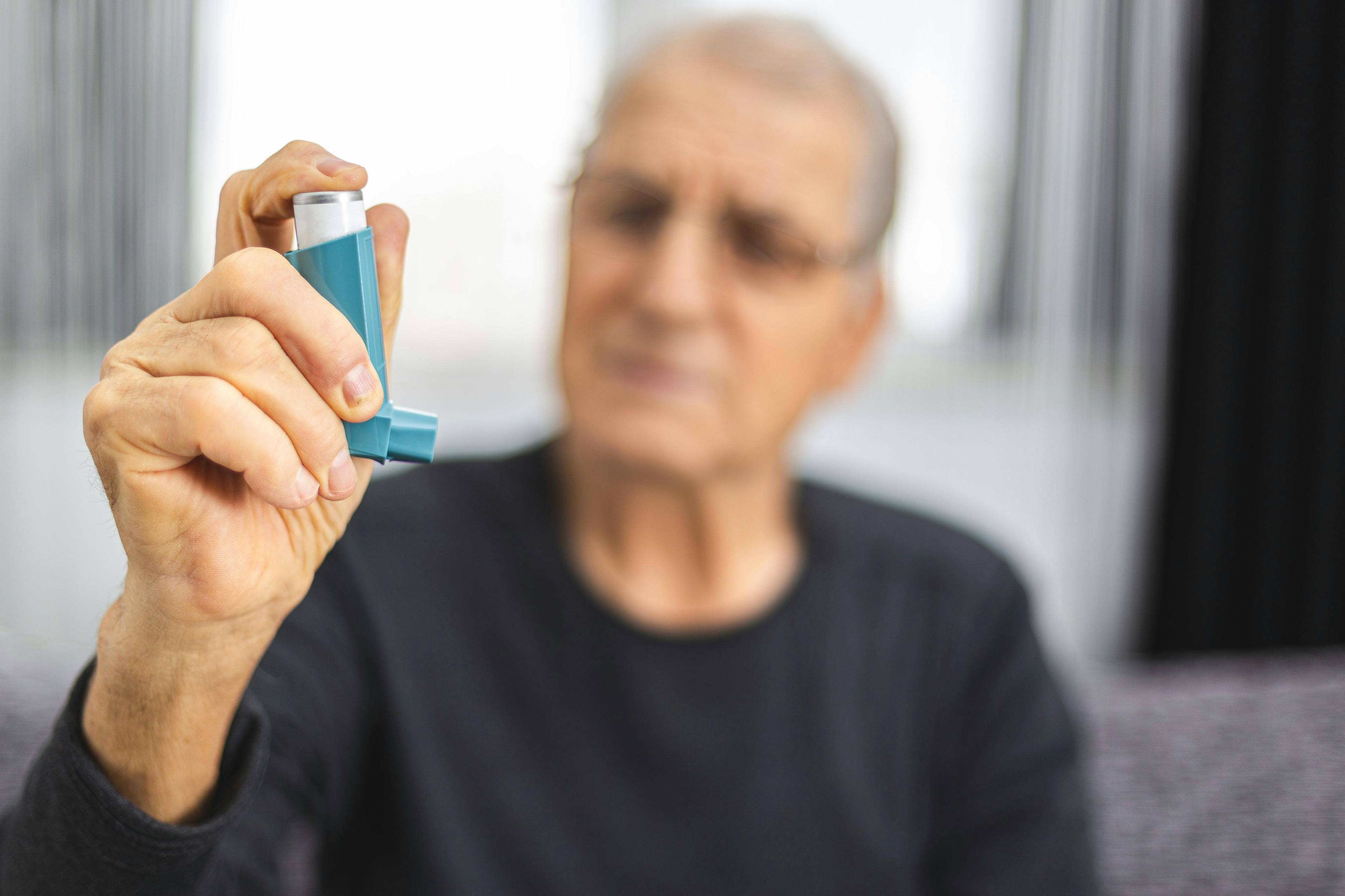 Elderly person holding an asthma inhaler