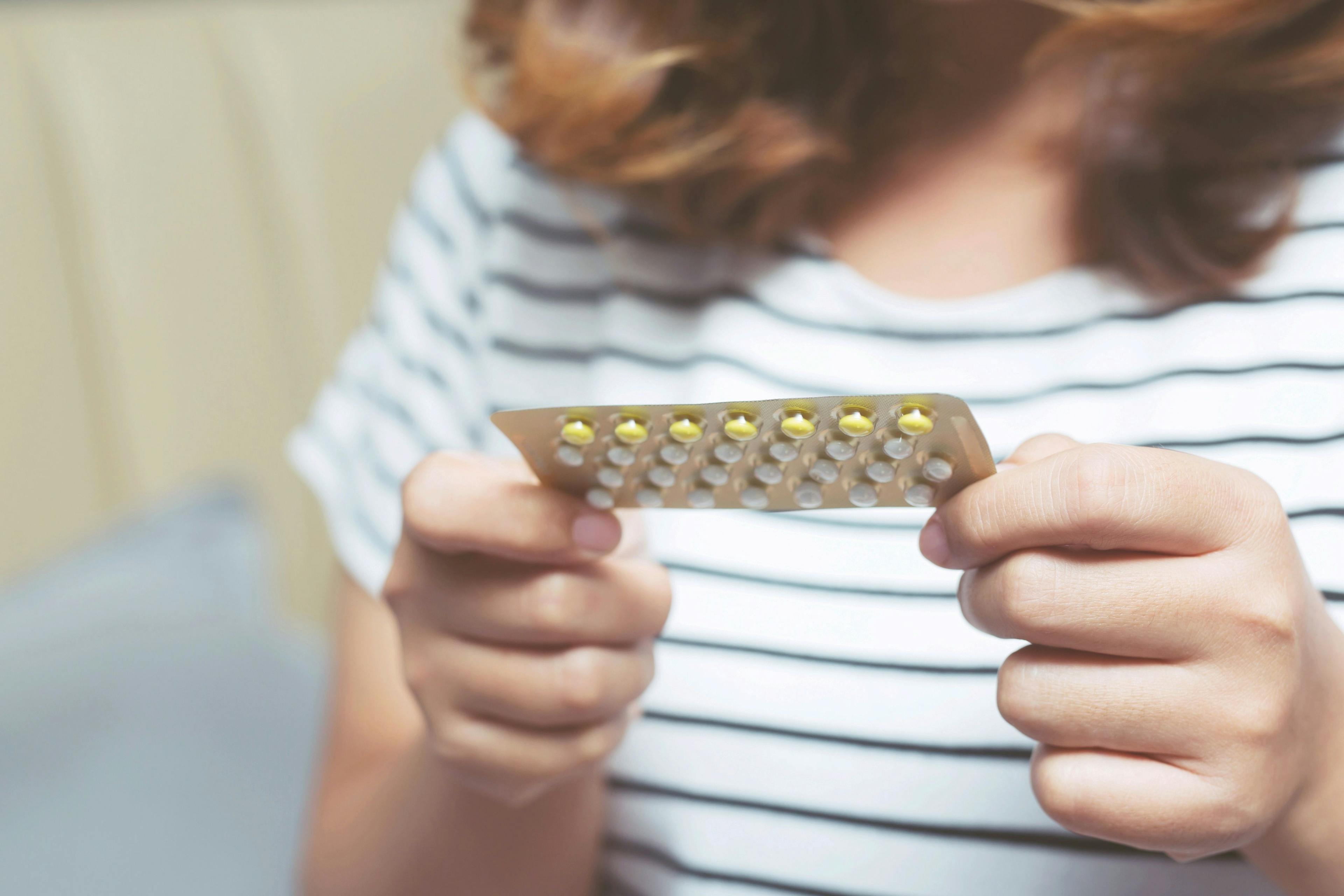 Woman holding birth control pills -- Image credit: methaphum | stock.adobe.com