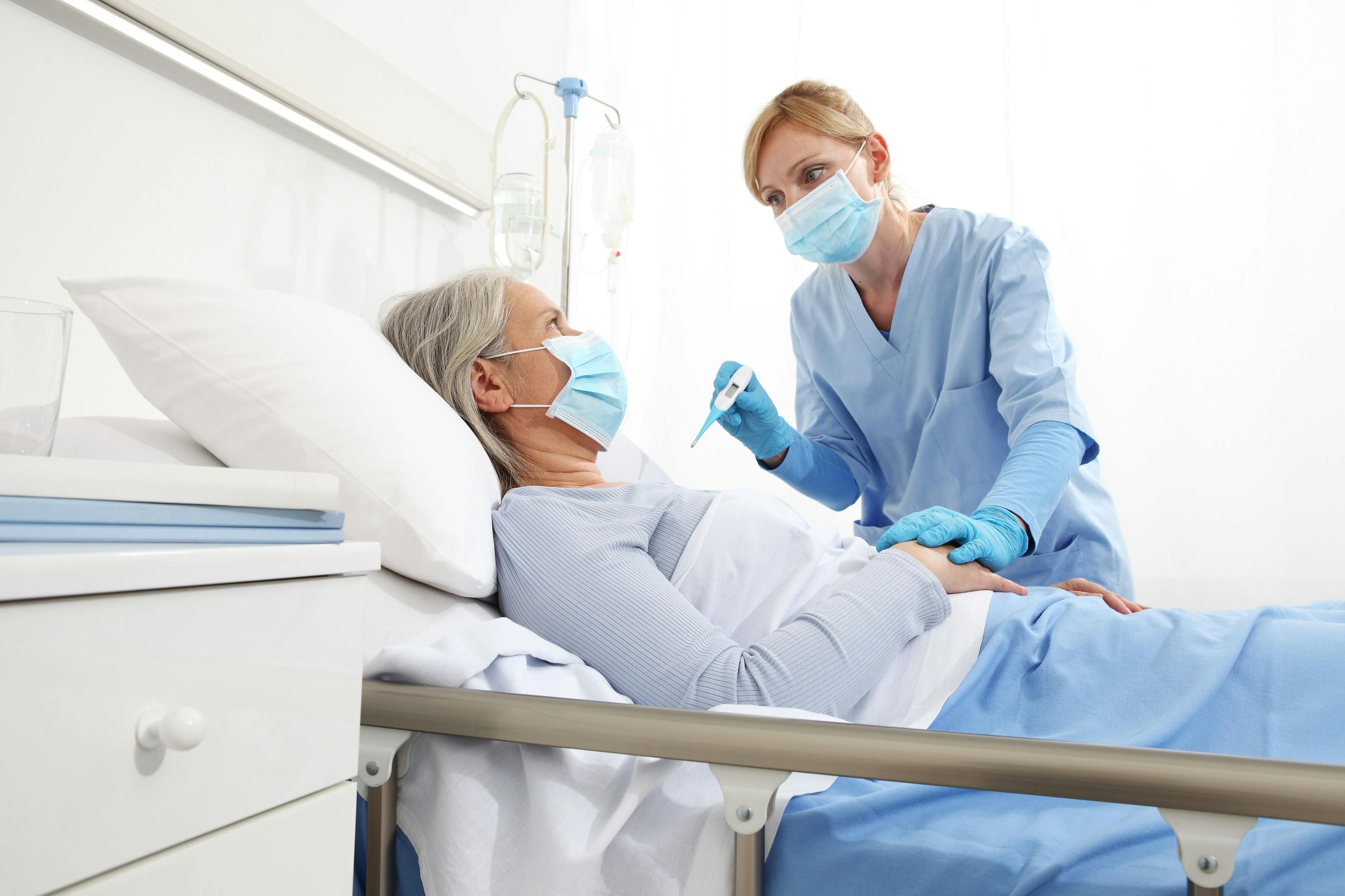 Health care worker taking a hospitalized patient's temperature