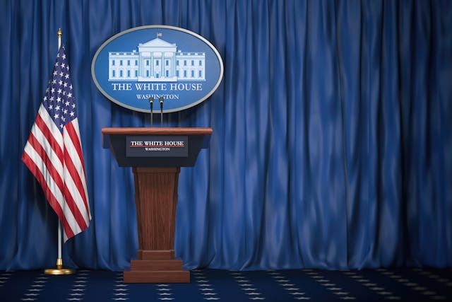 Podium speaker tribune with USA flags and sign of White House with space for text. Briefing of president of US United States in White House.Politics concept - Image credit: Maksym Yemelyanov | stock.adobe.com
