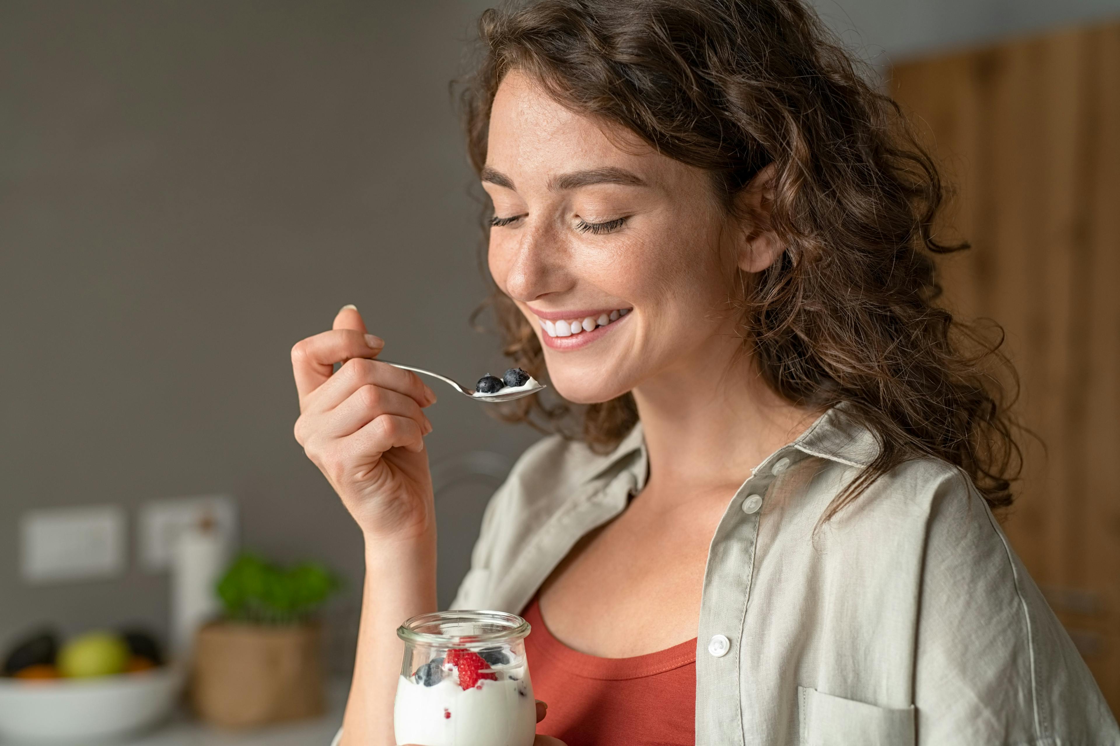 Woman eating yogurt with berries at home | Image Credit: Rido - stock.adobe.com