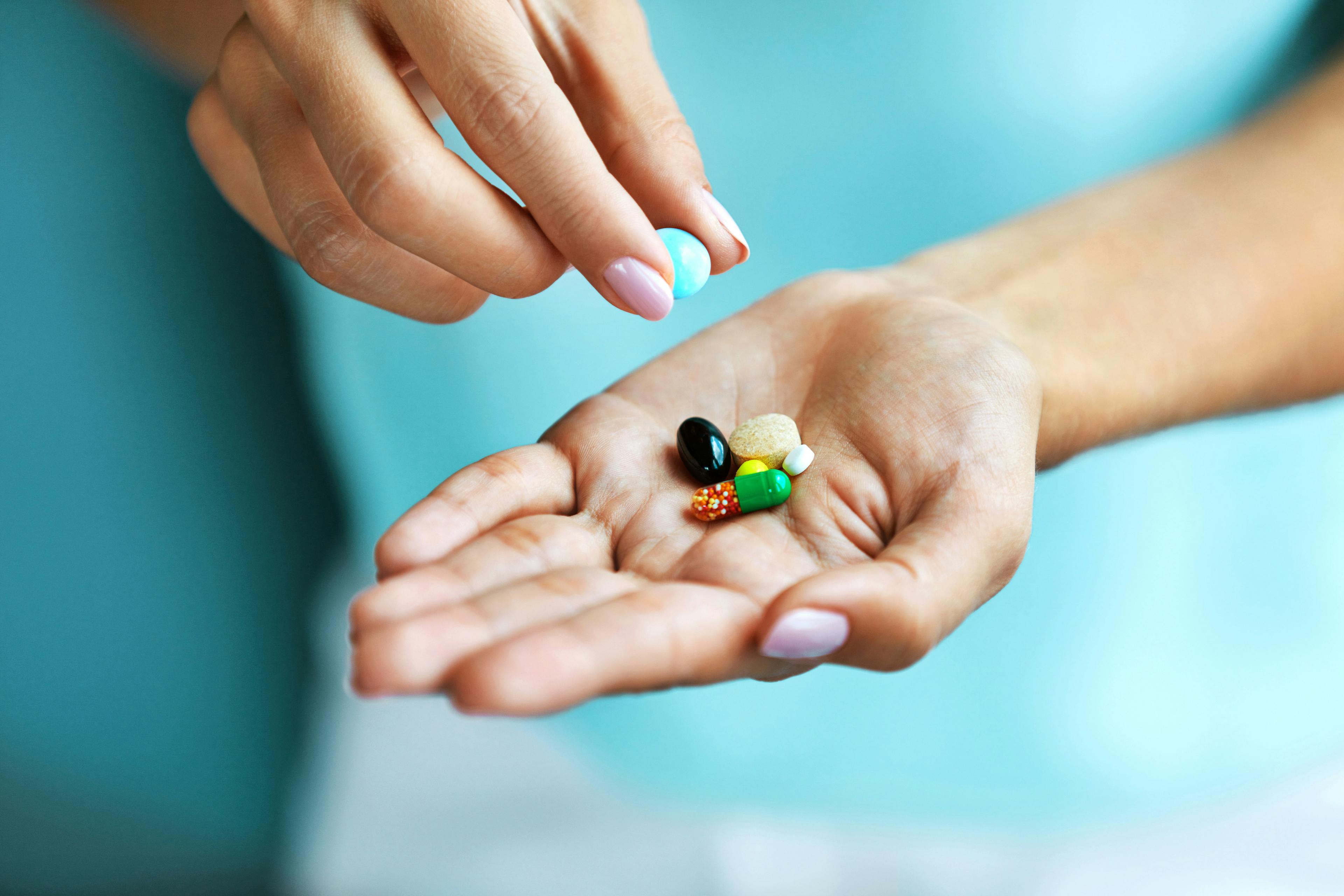 Vitamins And Supplements. Female Hand Holding Colorful Pills