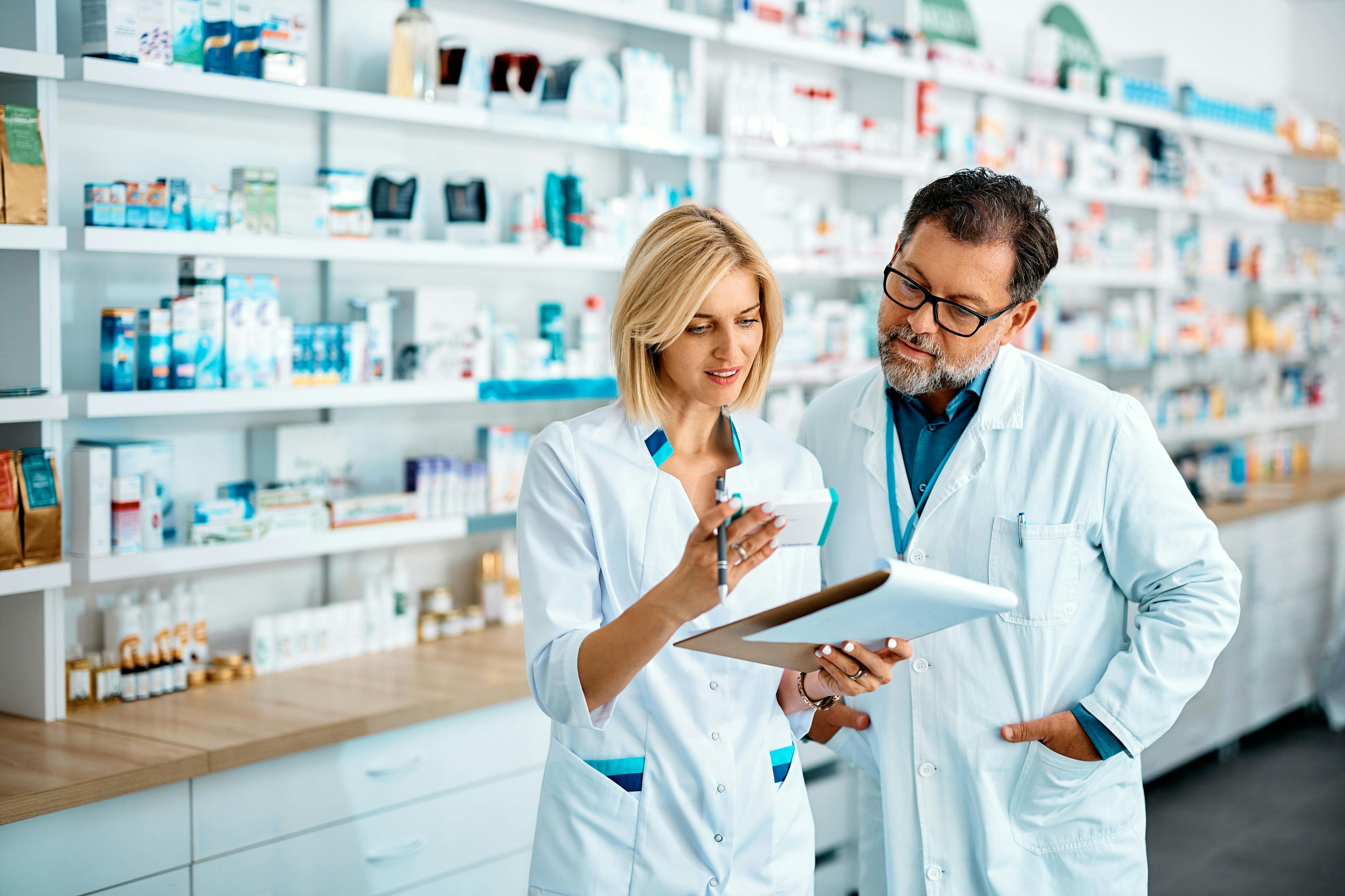 Female pharmacist and her male colleague checking inventory while working in pharmacy. | Image Credit: Drazen - stock.adobe.com