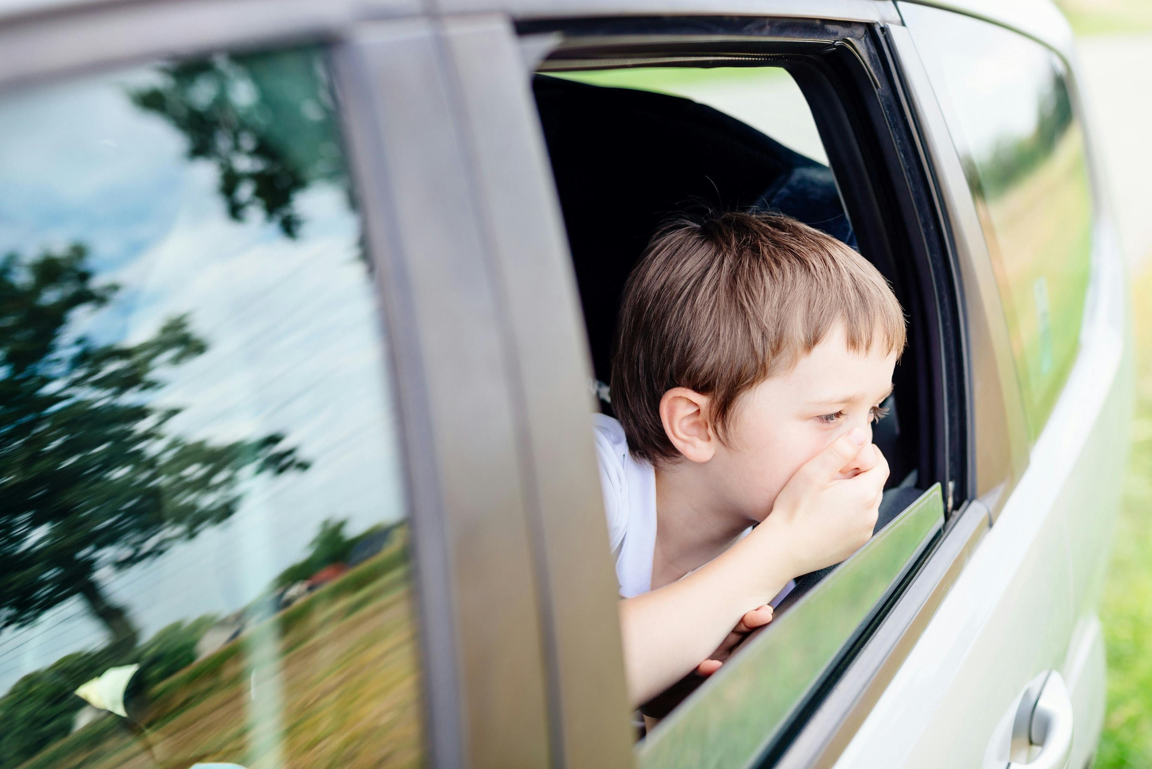 Child with motion sickness in the window of a car