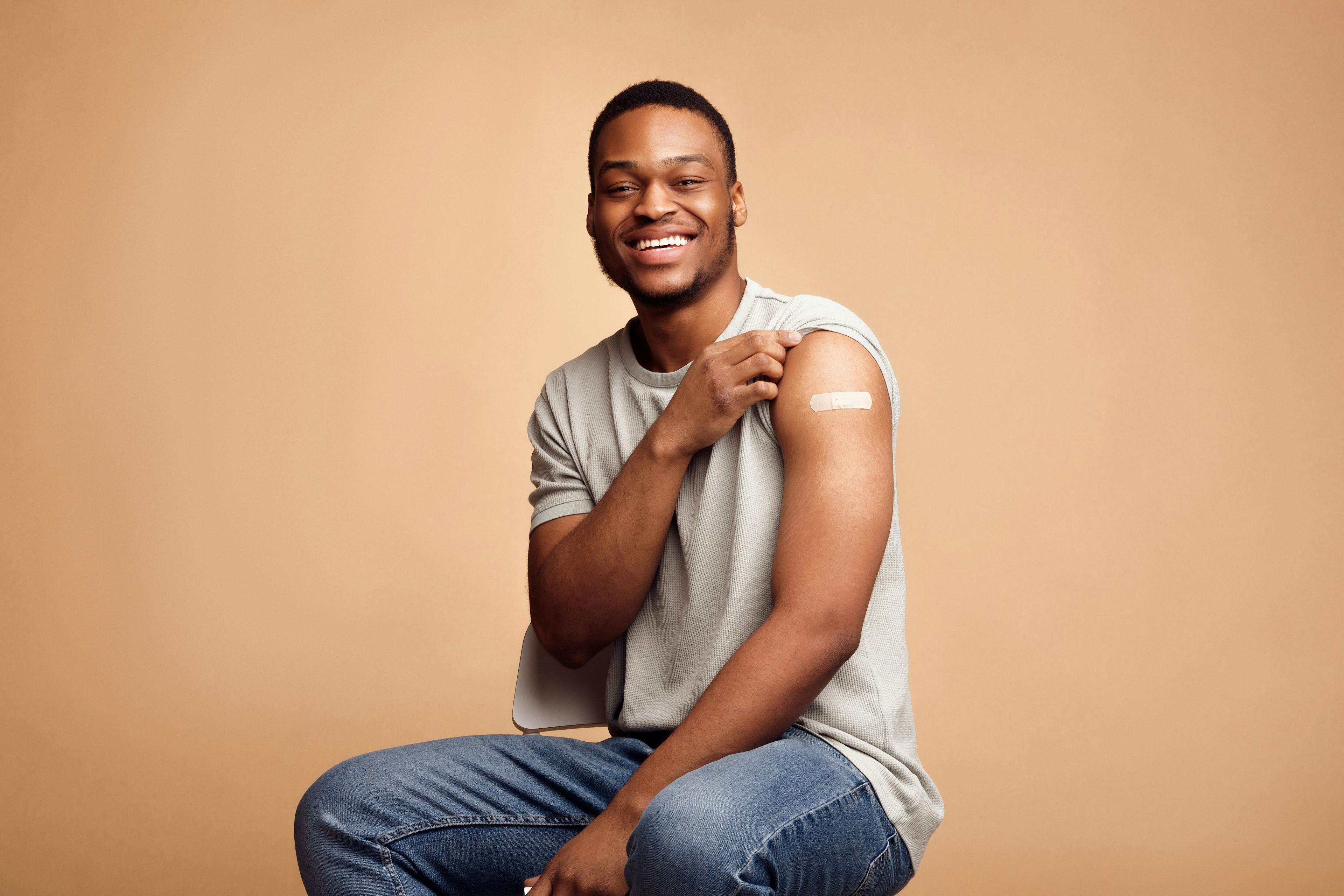Man showing vaccinated arm with band-aid
