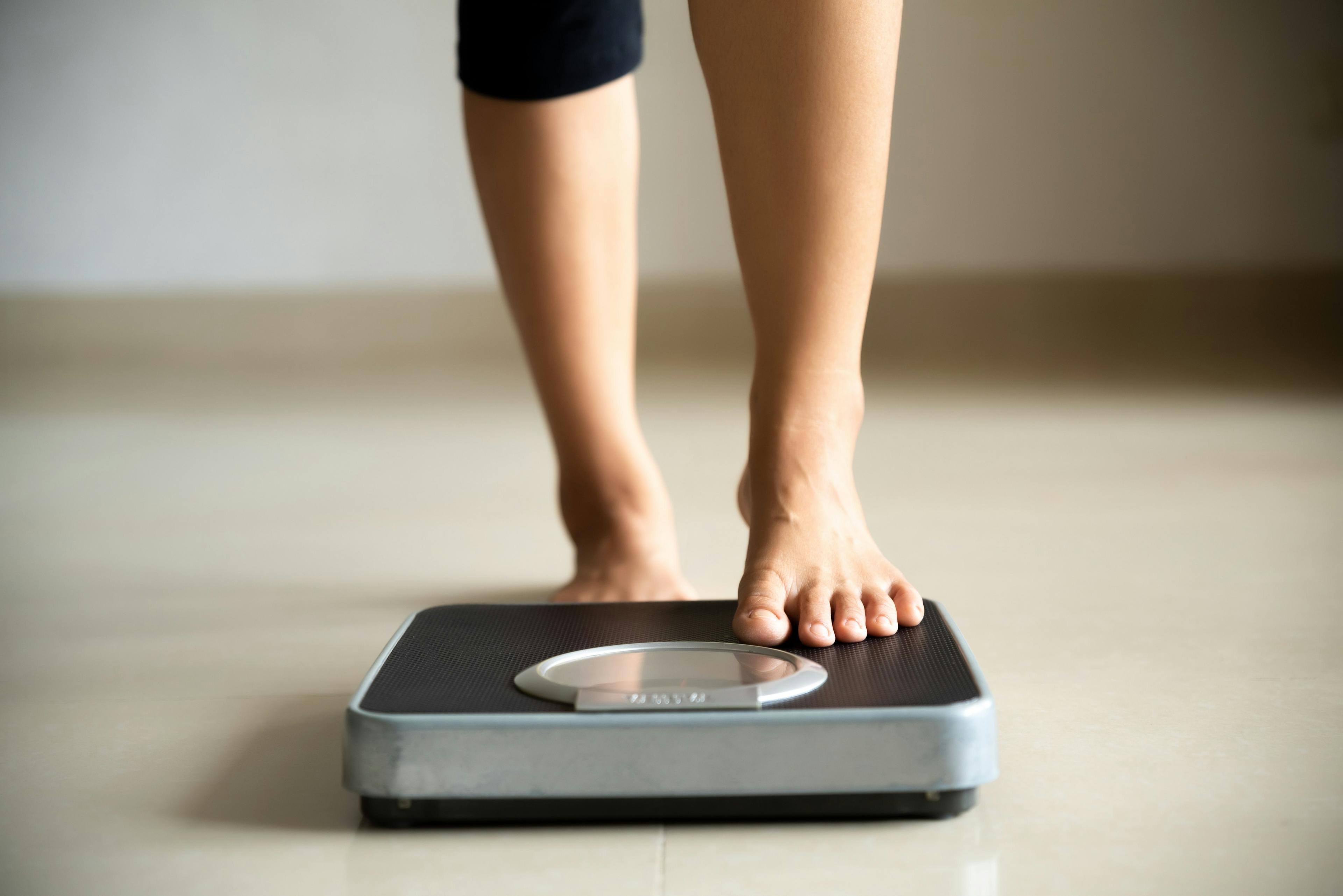 Woman stepping onto an electronic scale -- Image credit: Siam | stock.adobe.com