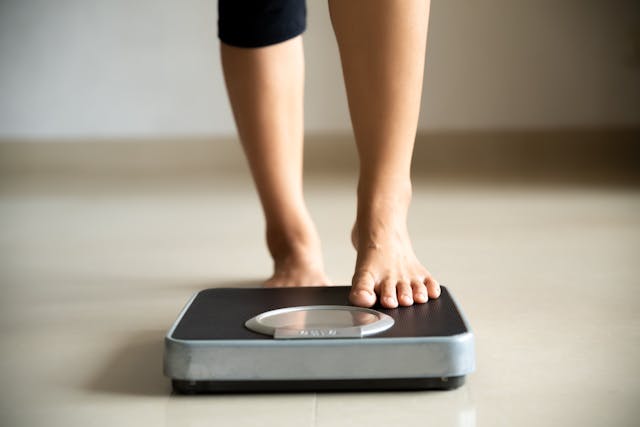 Woman stepping onto an electronic scale -- Image credit: Siam | stock.adobe.com