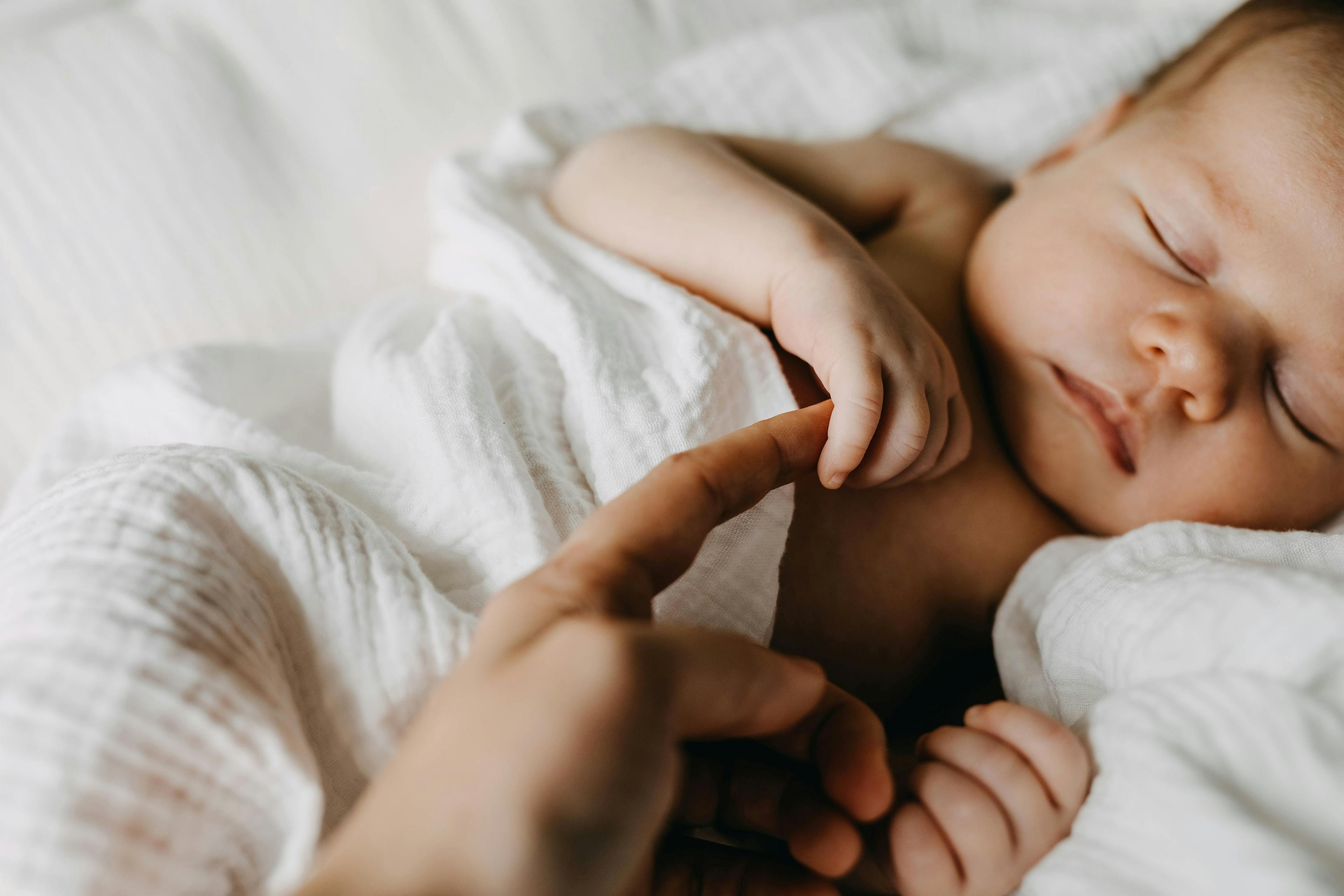 Infant holding their mother's finger